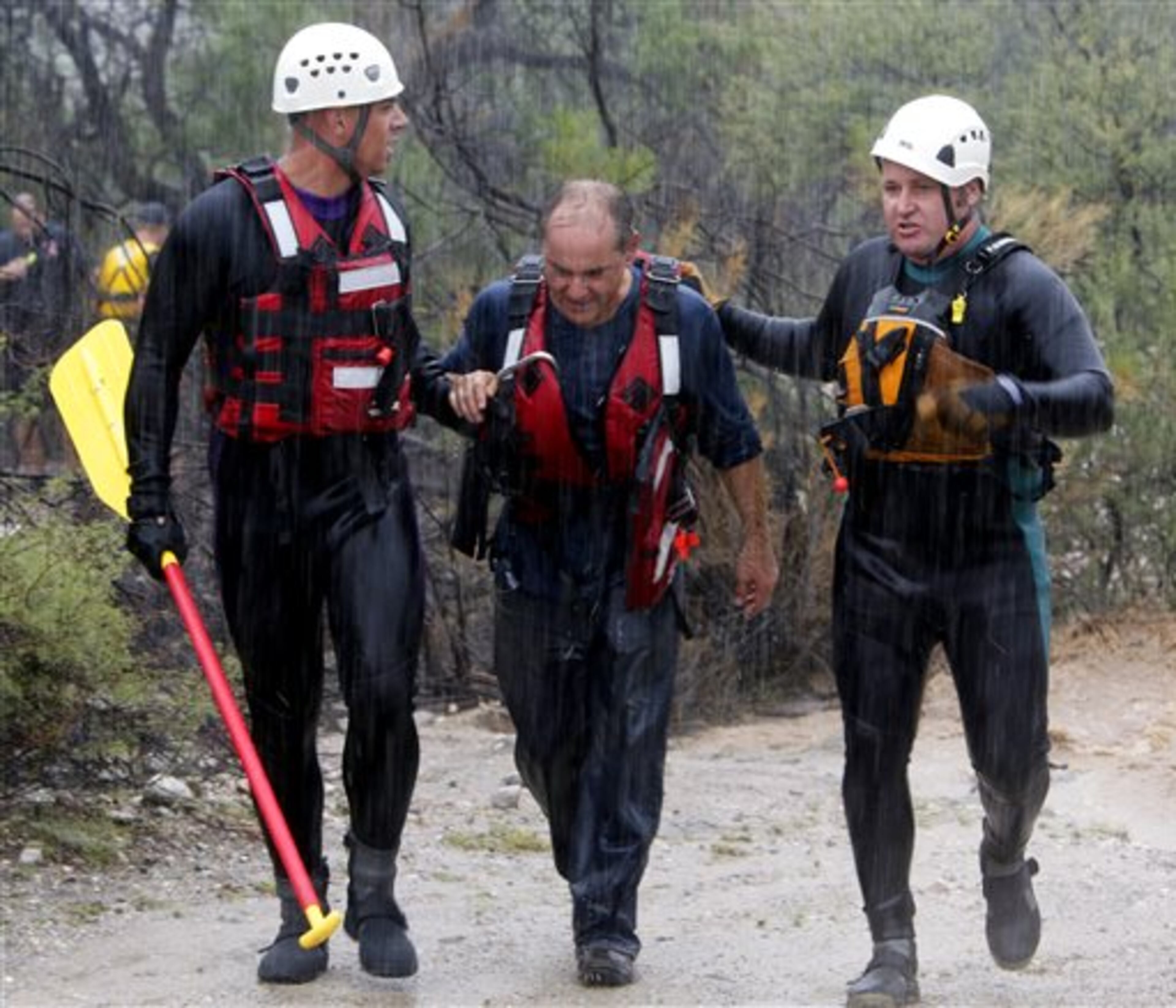 Northwest Fire District Technical rescue team members Mike Schindler, left, and Shawn Twilling, right, lead a driver to safety after his car was swept off the road north of Tucson, Ariz. on Monday, Sept. 8, 2014. The Phoenix and Tucson metro areas were hit by heavy rains, causing flooding and damage. More than 3 inches of rain closed parts of several Phoenix freeways. In Tucson, the National Weather Service recorded nearly 2 inches of rain. (AP Photo/Arizona Daily Star, Ron Medvescek)