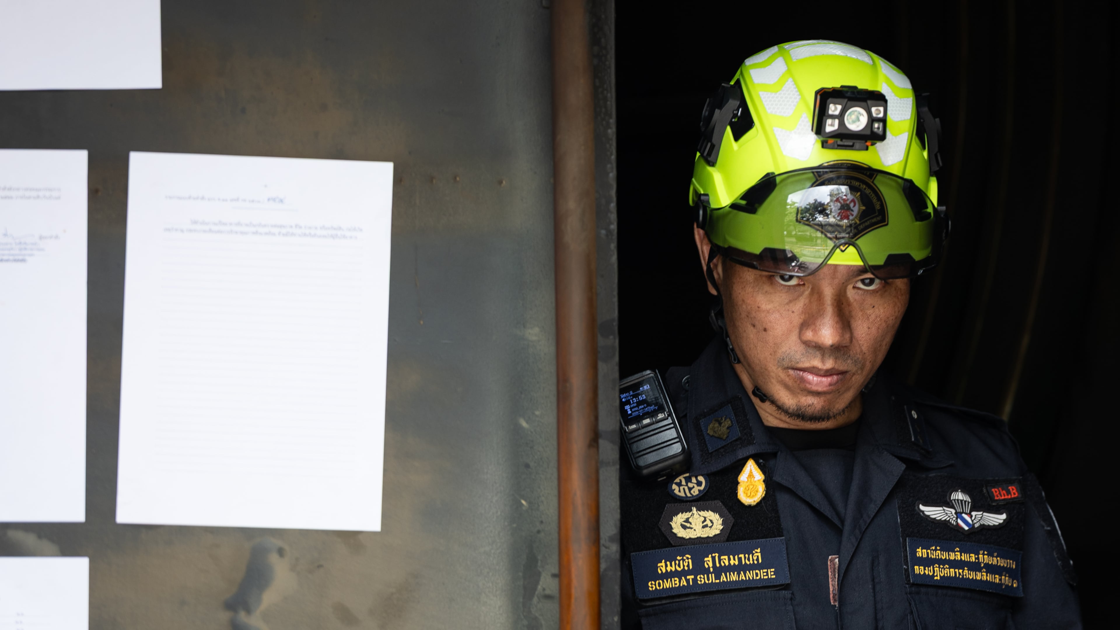 A rescuer looks on at the entrance door of the music bar where a fire killed a number of people in Bangkok, Thailand, Tuesday, July 14, 2026. (AP Photo/Wason Wanichakorn)