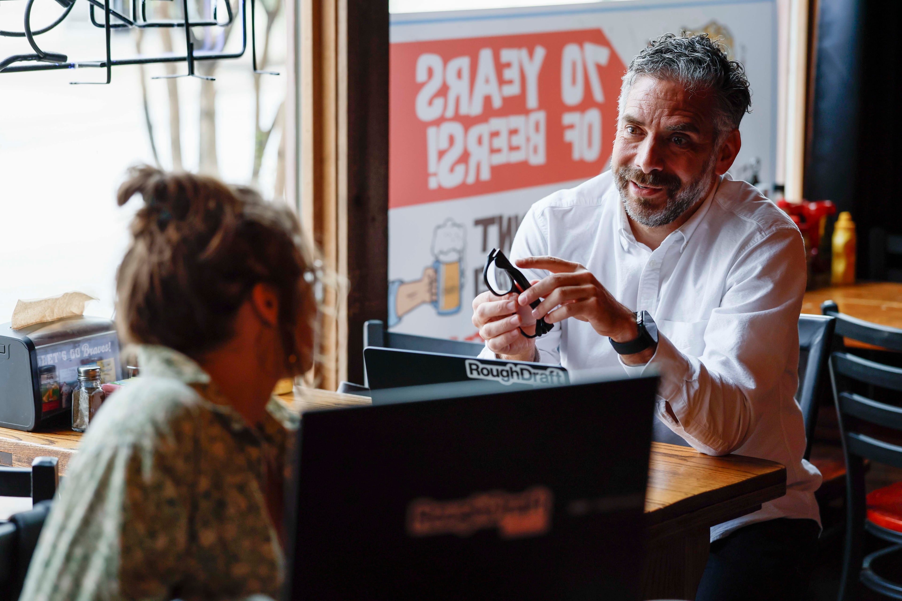 Rough Draft Publisher Keith Pepper speaks with Executive Assistant Savannah Pierce during a staff meeting at Manuel’s Tavern on Thursday, October 1, 2026. With a print circulation of 70,500 across five Atlanta communities, Rough Draft is launching a print edition in Athens. (Miguel Martinez/AJC)