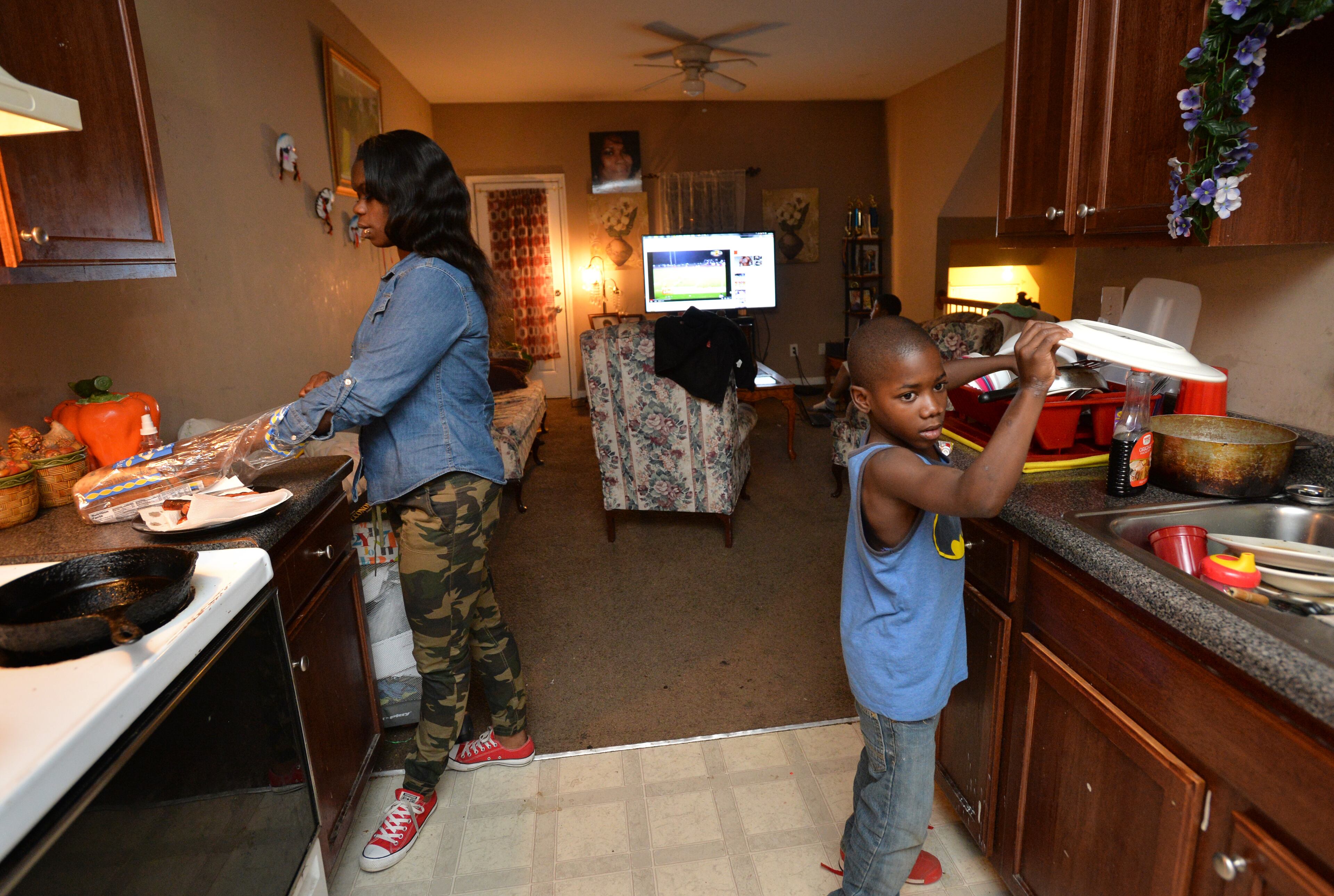 Ashley Roberson (left), 23, makes hotdogs for her brothers as her youngest brother Damyuss Marshall, 8, helps at their home in Atlanta. HYOSUB SHIN / HSHIN@AJC.COM