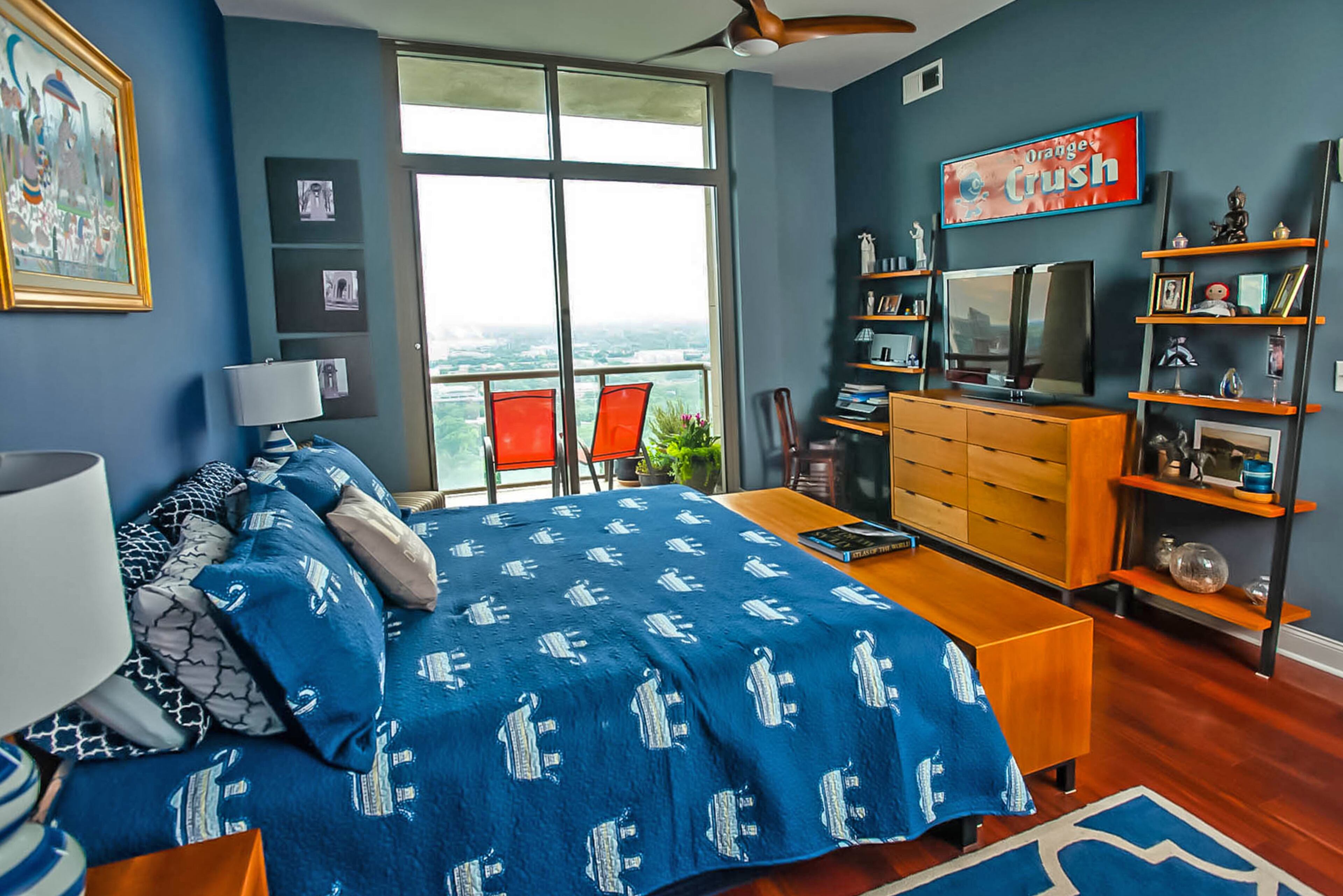 Modern open shelving and a dresser from Room & Board' Copenhagen collection anchor a wall in the blue-hued master bedroom. Like other rooms in their Atlantic condo, the bedroom has floor-to-ceiling windows.