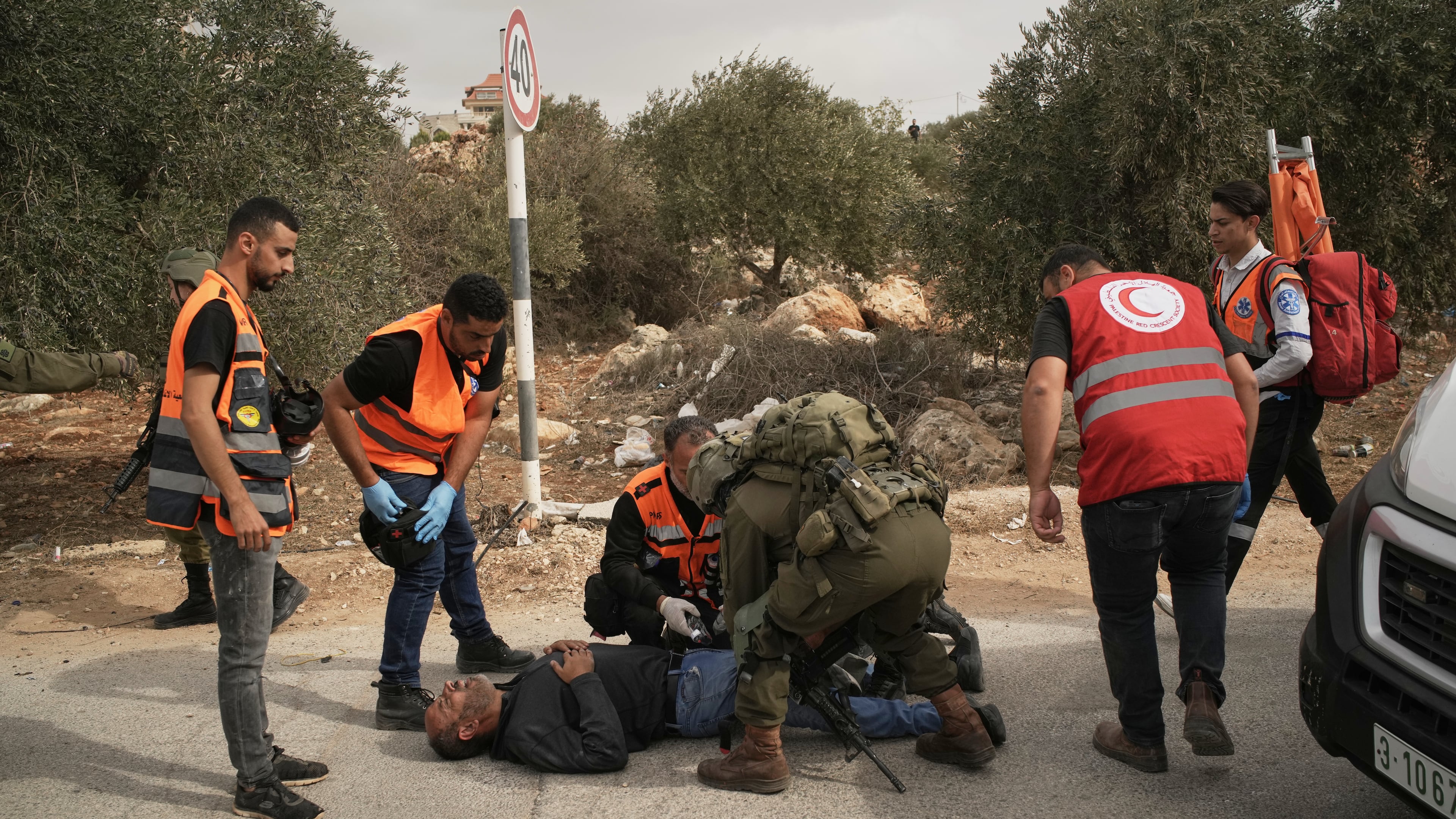 Palestinian medics and an Israeli soldier attend to a Palestinian man shot by Israeli soldiers following a settler attack on Palestinians harvesting olives in the West Bank village of Abu Falah, Friday, Oct. 16, 2026. (AP Photo/Leo Correa)