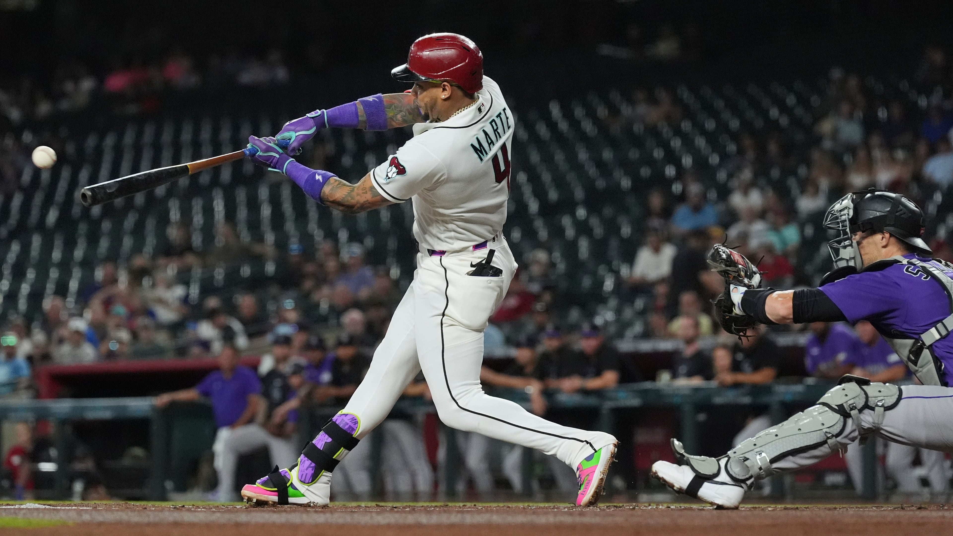 Arizona Diamondbacks' Ketel Marte (4) hits a run-scoring single as Colorado Rockies catcher Brett Sullivan reaches for the ball during the first inning of a baseball game, Wednesday, Aug. 12, 2026, in Phoenix. (AP Photo/Ross D. Franklin)