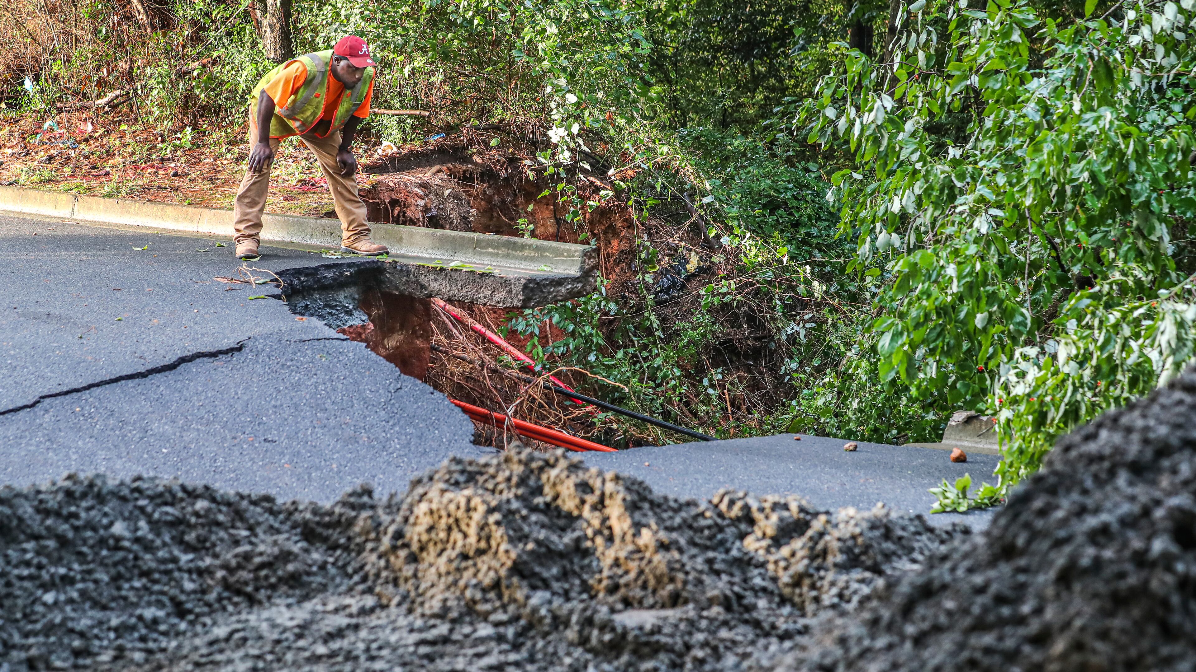 A worker surveys damage from a road that was washed away in Marietta after heavy rains fell Sept. 8. Cobb County commissioner Jerica Richardson will be hosting a community meeting at 5:30 p.m. Thursday to hear input from residents affected by the storm. (AJC File)