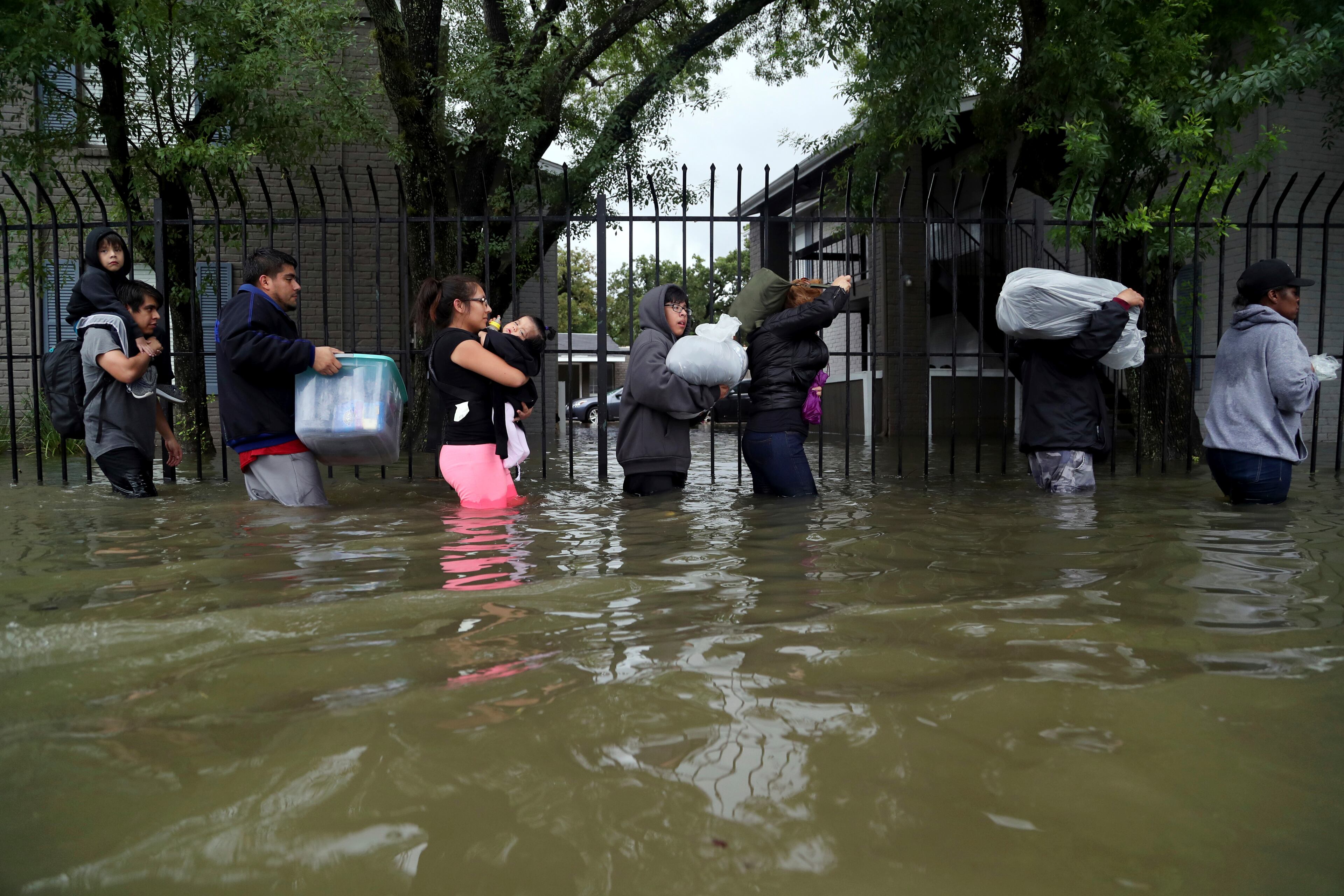 Residents from Bayou Parc at Oak Forest carry their belongings while evacuating the apartment complex during the Tropical Storm Harvey, Sunday, Aug. 27, 2017, in Houston. The remnants of Hurricane Harvey sent devastating floods pouring into Houston Sunday as rising water chased thousands of people to rooftops or higher ground. (Marie D. De Jesus/Houston Chronicle via AP)