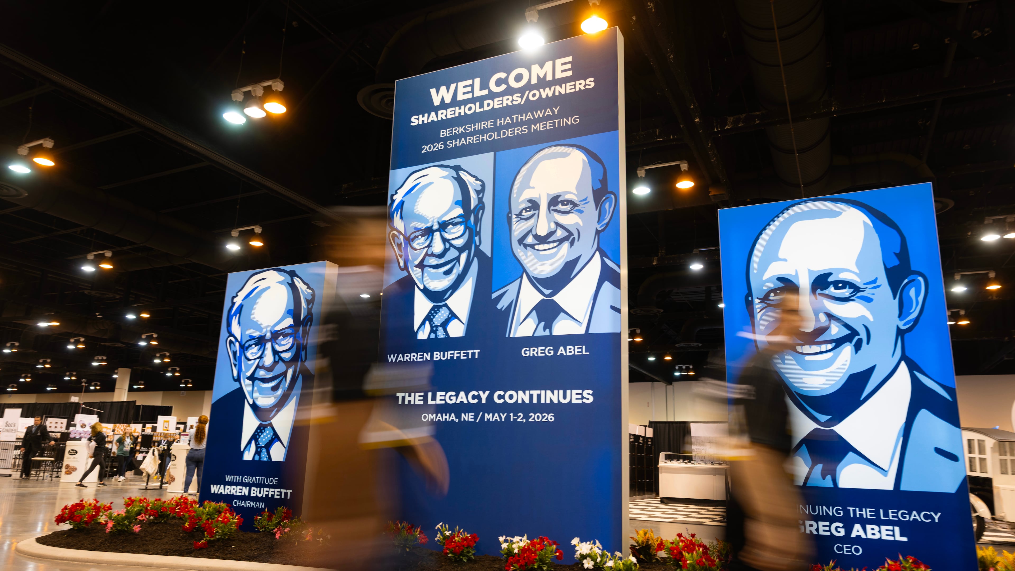 People walk past large portraits of Berkshire Hathaway's Warren Buffett, left, and CEO Greg Abel inside the Berkshire Hathaway annual meeting on Saturday, May 2, 2026, in Omaha, Neb. (AP Photo/Rebecca S. Gratz)