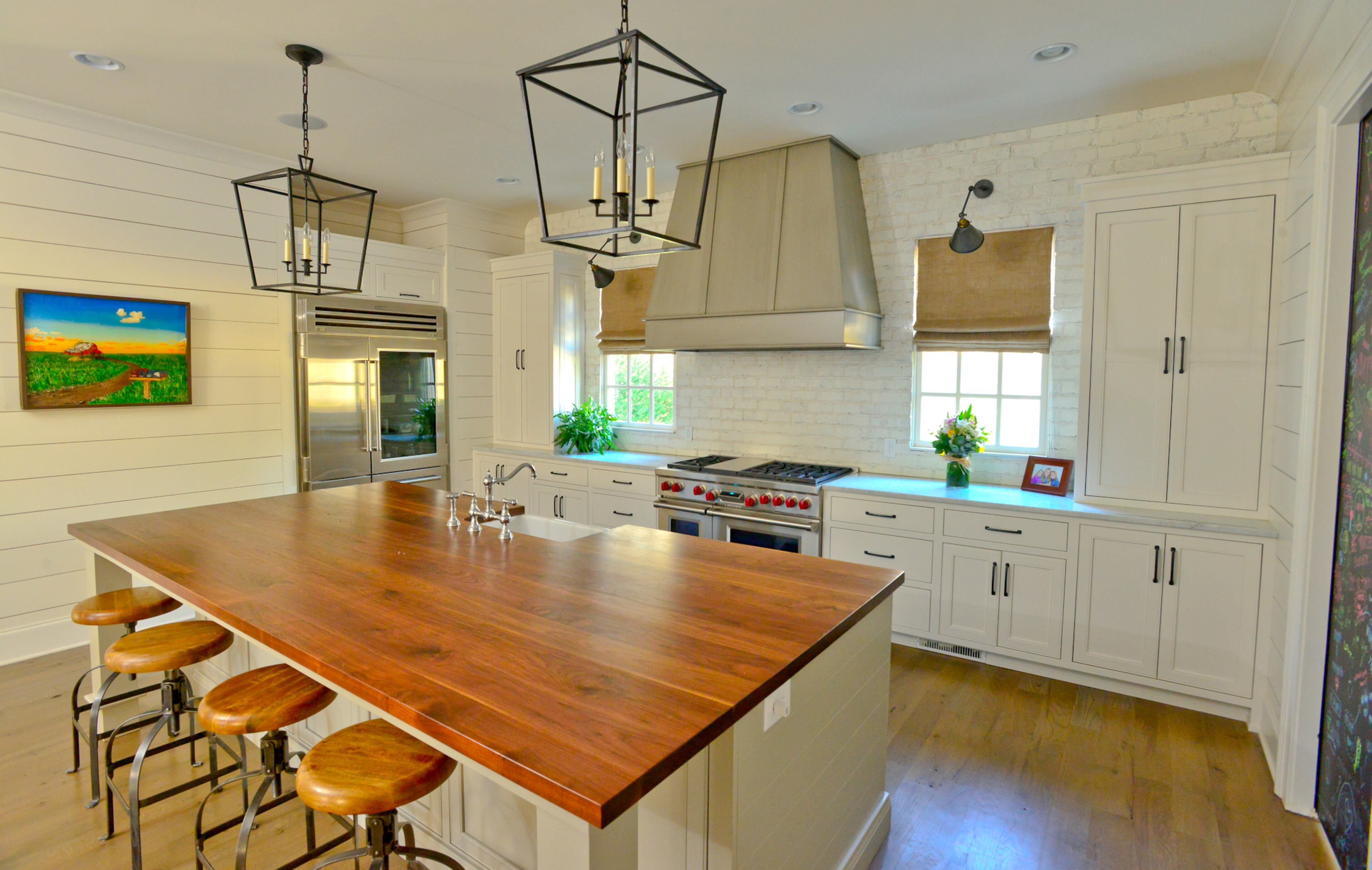 Appliances by Wolf and Sub-Zero and lighting from RH stand out against the all-white shiplap and brick walls and cupboards, while artwork from Jeff Reed injects a splash of vibrant color. The island in the Milton kitchen has a walnut-stained countertop. Text by Lori Johnston and Keith Still/Fast Copy News Service. (Christopher Oquendo Photography/www.ophotography.com)