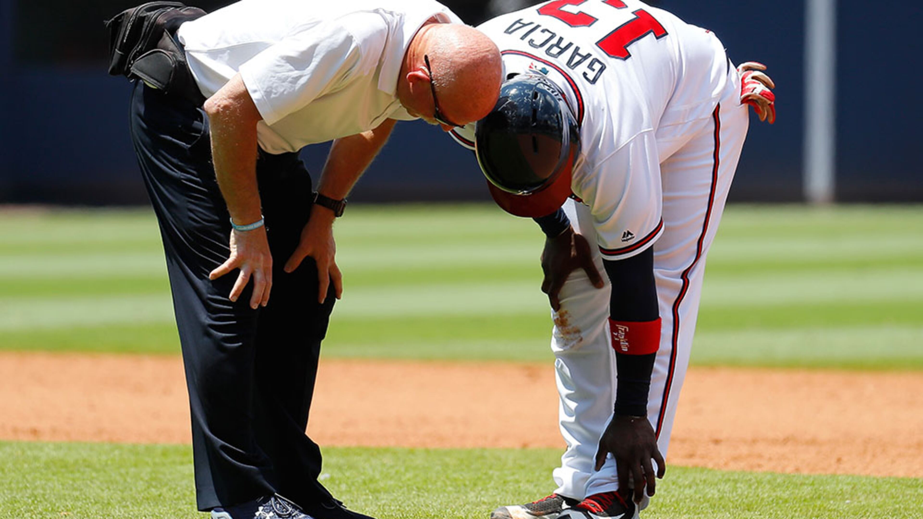 Adonis Garcia converses with trainer Jeff Porter in the seventh inning prior to being replaced by a pinch runner against the Cincinnati Reds Thursday, June 16, 2016, at Turner Field in Atlanta.