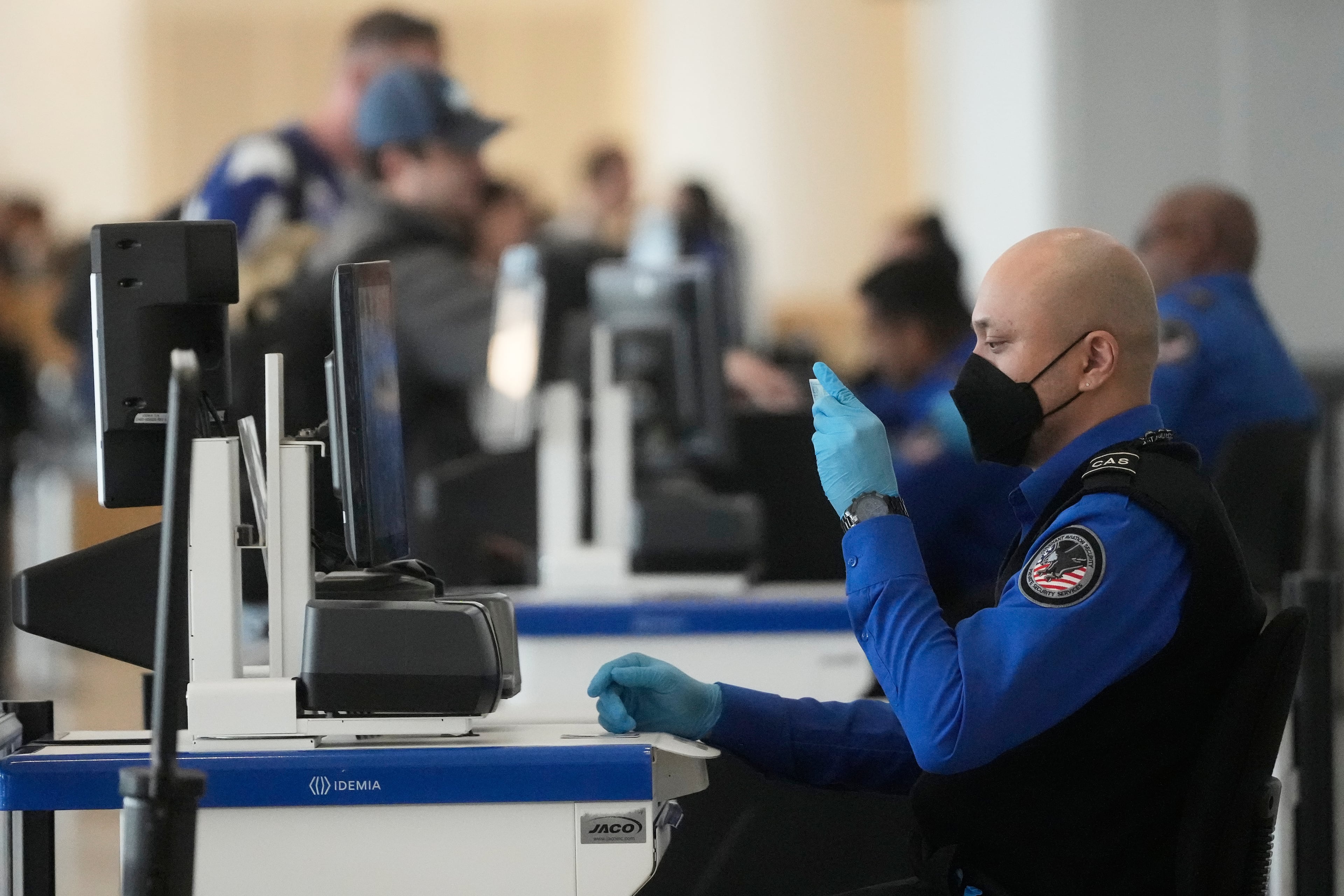 A Covenant Aviation Security Private Security Services agent checks the identification of a passenger at a security gate at San Francisco International Airport last month. SFO is the largest of about 20 airports that have private companies handling security screening. (Jeff Chiu/AP)