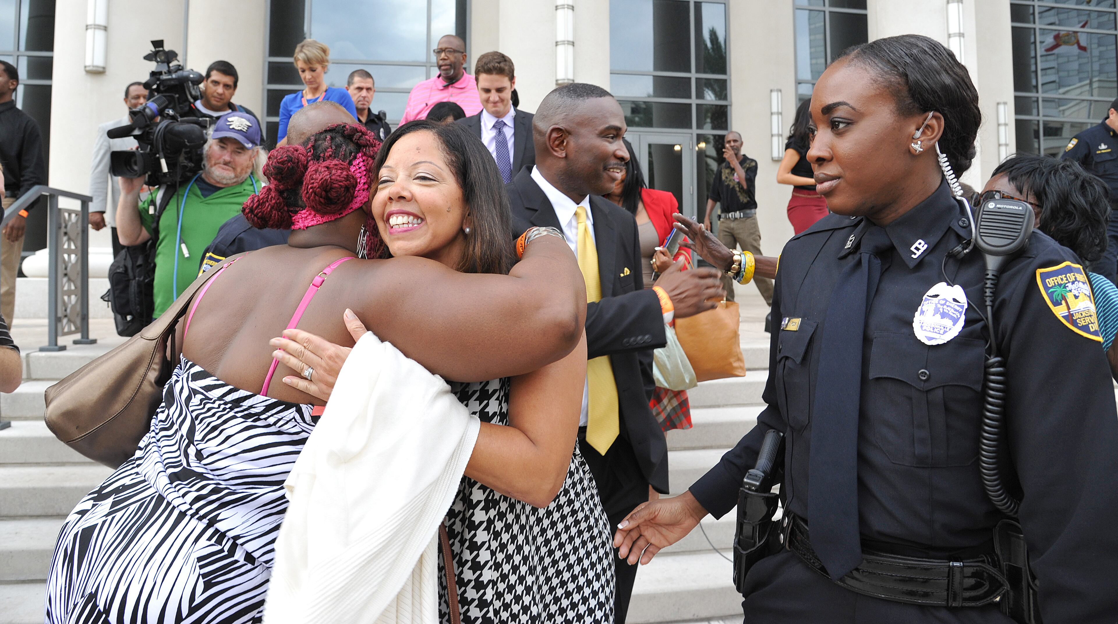 Jordan Davis' parents Lucia McBath, second from left, and Ronald Davis, center, rear, are greeted by supporters as they leave the Duval County Courthouse on Wednesday, Oct. 1, 2014 in Jacksonville, Fla. A jury convicted Micheal Dunn on Wednesday of first-degree murder in his retrial for killing teenager Jordan Davis after an argument over loud music. (AP Photo/The Florida Times-Union, Bruce Lipsky)
