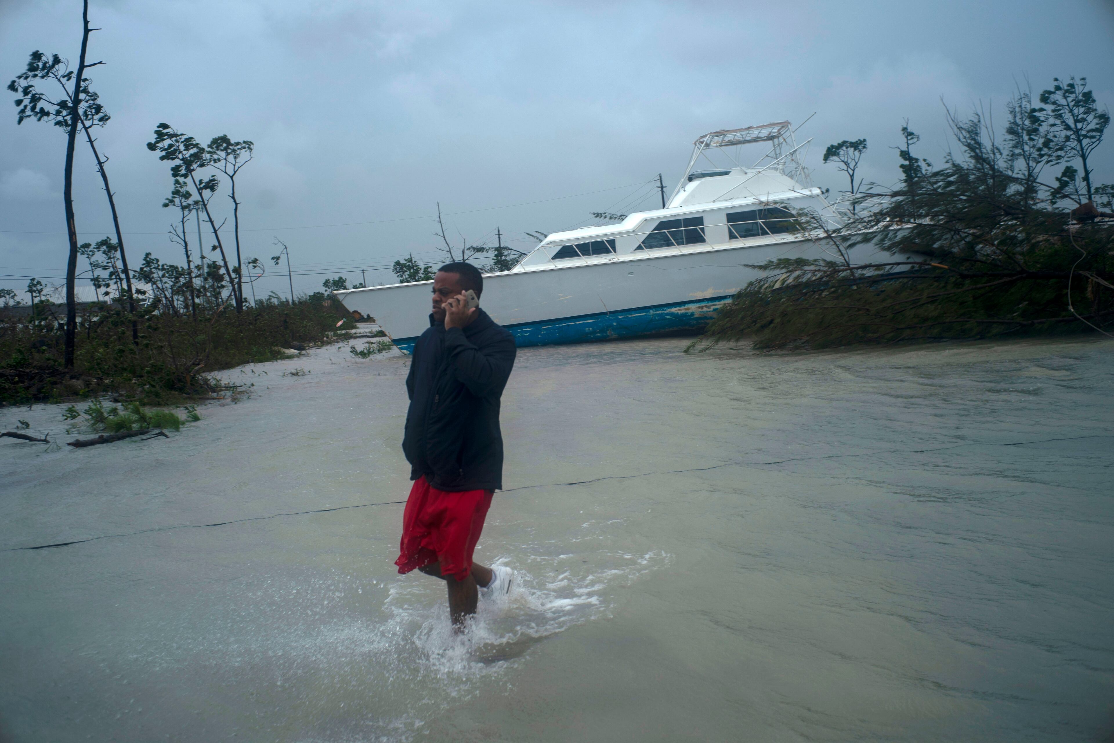 A man talks on his mobile phone next to a catamaran that was thrown onshore by the Hurricane Dorian near highway close Freeport, Grand Bahama, Bahamas, Tuesday Sept. 3, 2019. Relief officials reported scenes of utter ruin in parts of the Bahamas and rushed to deal with an unfolding humanitarian crisis in the wake of Hurricane Dorian, the most powerful storm on record ever to hit the islands. (AP Photo/Ramon Espinosa)