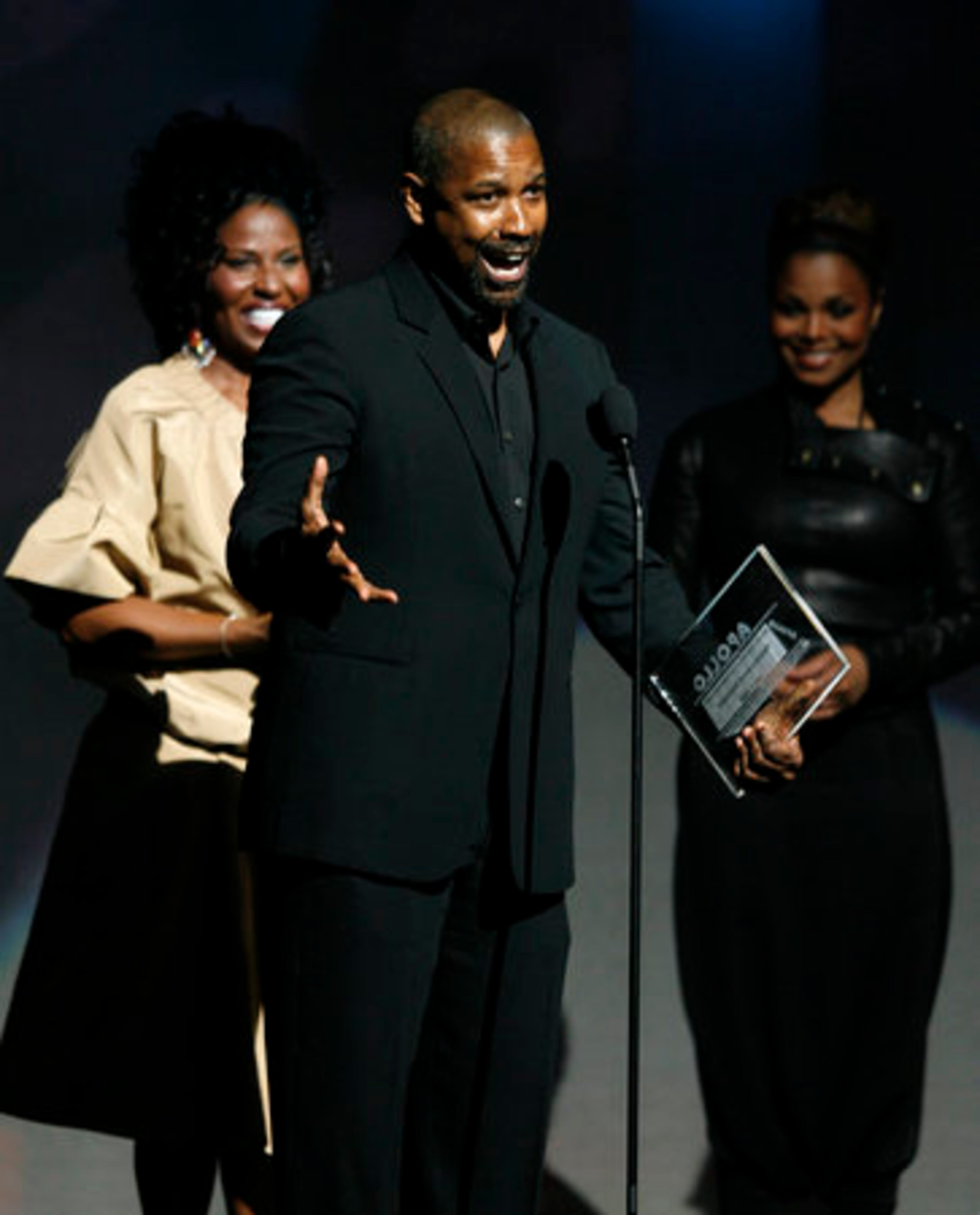Flanked by his wife Pauletta, (left) and singer Janet Jackson, (right) actor Denzel Washington accepts the Apollo's Humanitarian Award.
