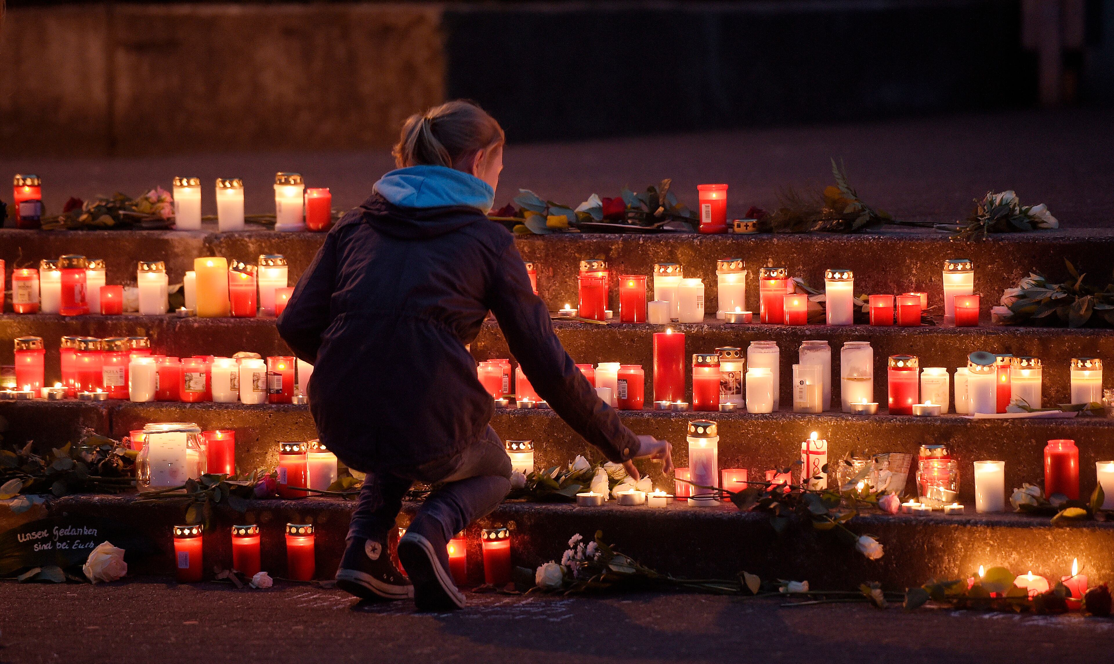 A school girl lights a candle in front of the Joseph-Koenig Gymnasium in Haltern, western Germany Tuesday, March 24, 2015. A Germanwings plane from Barcelona crashed on its way to Duesseldorf over the French alps, 16 school children and 2 teachers from Haltern were among the 150 people on board. (AP Photo/Martin Meissner)