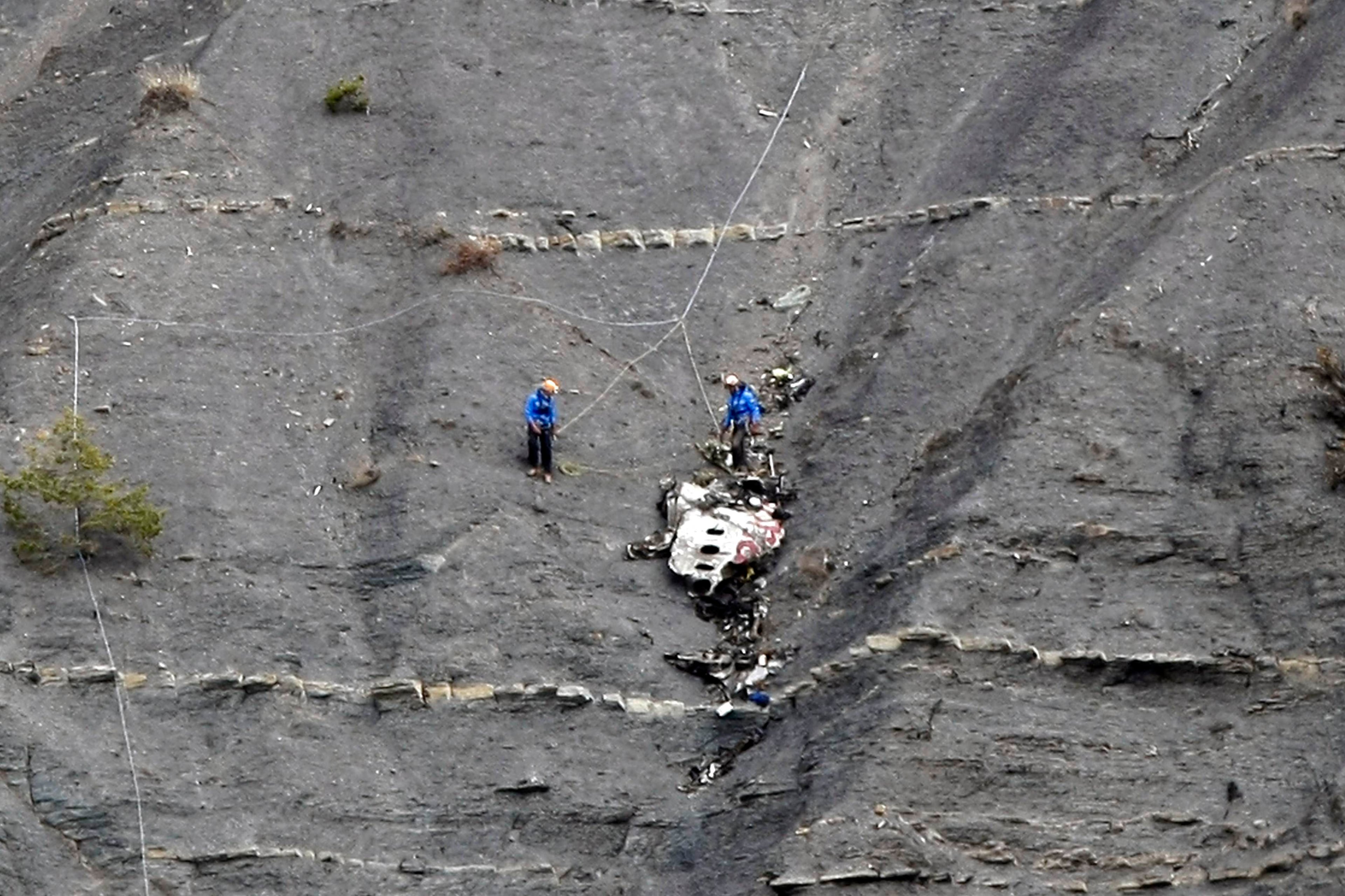 Rescue workers are seen near debris at the crash site of the Germanwings Airbus A320 near Seyne-les-Alpes, French Alps, March 30, 2015. The young German co-pilot, Andreas Lubitz, suspected of deliberately crashing a passenger plane in the French Alps, killing all 150 people on board including himself, told his girlfriend he was in psychiatric treatment, and that he was planning a spectacular gesture that everyone would remember, the German daily Bild reported on Saturday. REUTERS/Claude Paris/Pool