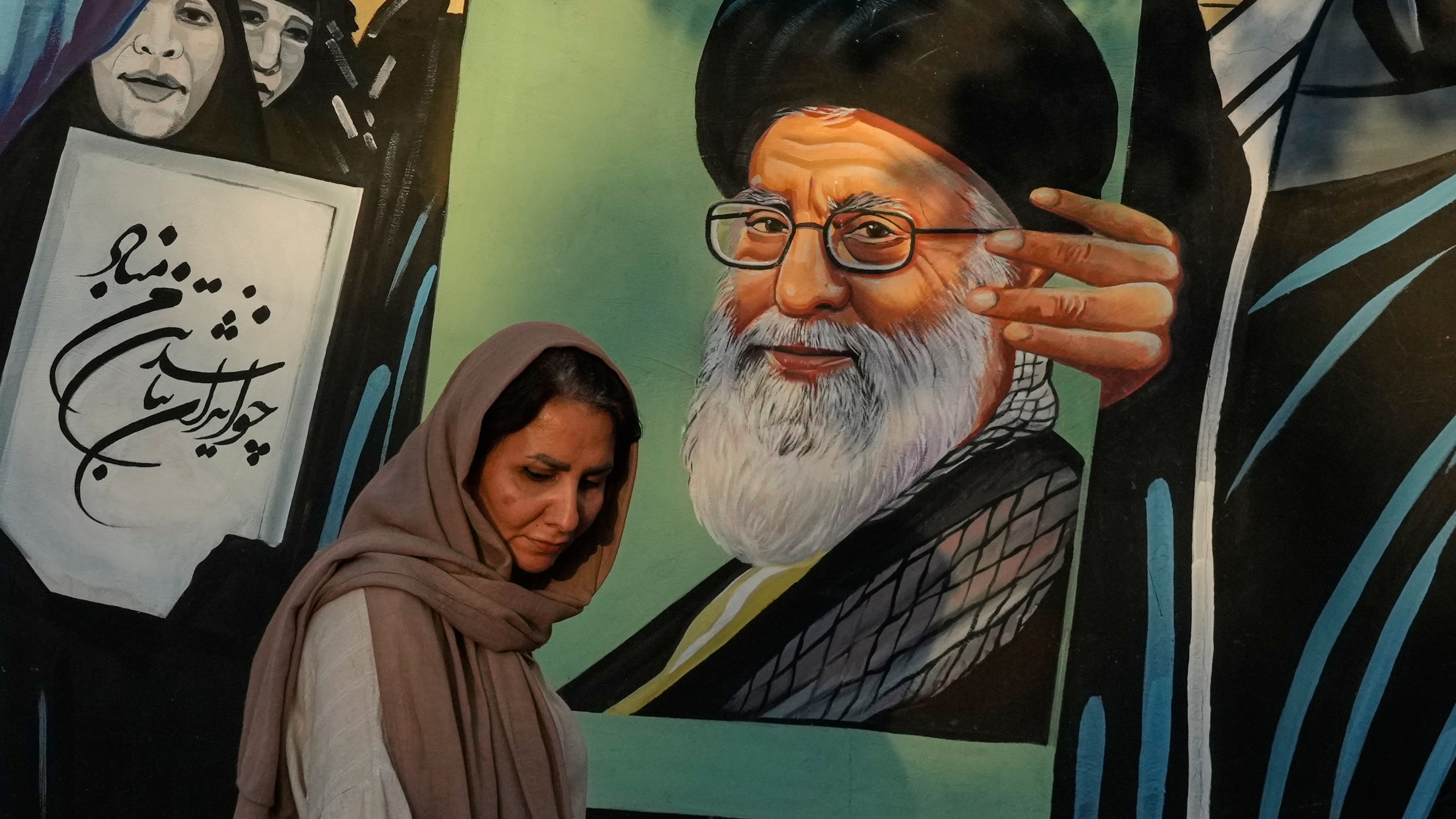 A woman walks past a mural depicting a portrait of the late Iranian Supreme Leader Ayatollah Ali Khamenei, who was killed in the U.S. and Israel strike on Feb. 28, in downtown Tehran, Iran, Saturday, July 18, 2026. (AP Photo/Vahid Salemi)