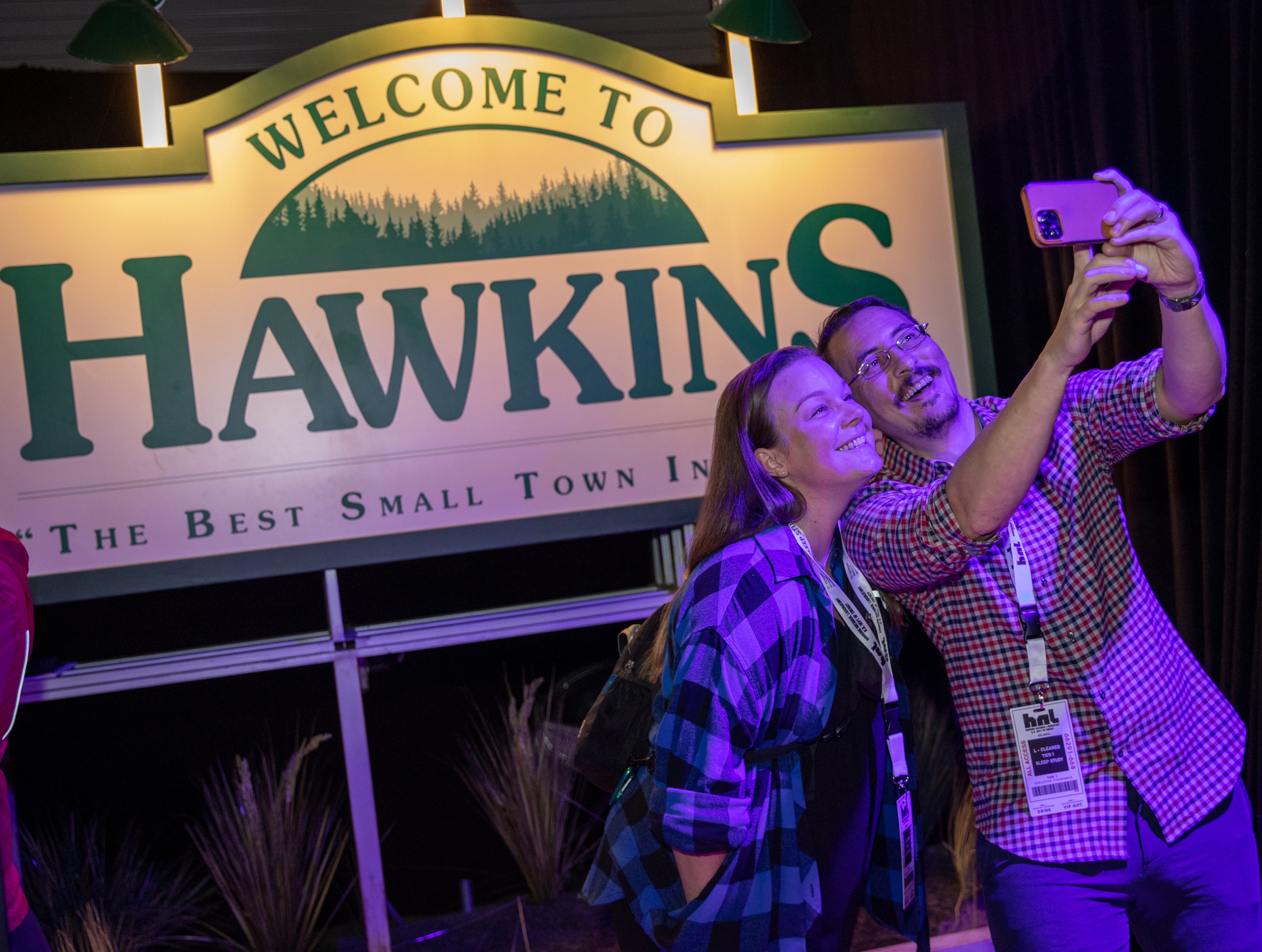 The "Stranger Things: The Experience" at Pullman Yards begins where Whitney and Adam Kemmerick of Kirkwood take pics with the Welcome to Hawkins sign on Friday, Nov. 11, 2022. (Jenni Girtman for The Atlanta Journal-Constitution)