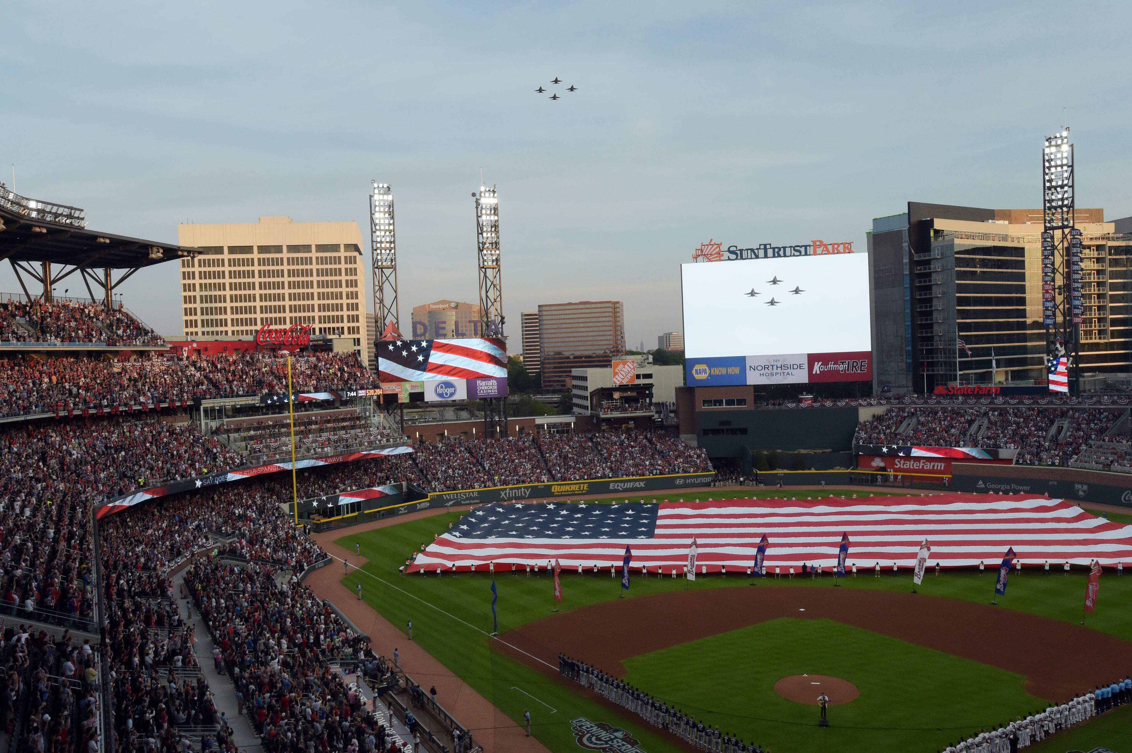 Braves staff holds the American flag on the field, United States Navy F/A-18A+ Hornets from VFC-12 out of Oceana, Va., perform a flyover at the conclusion of the national anthem before the Atlanta Braves play the San Diego Padres in the season opener in the new SunTrust Park Friday, April 14, 2017.
