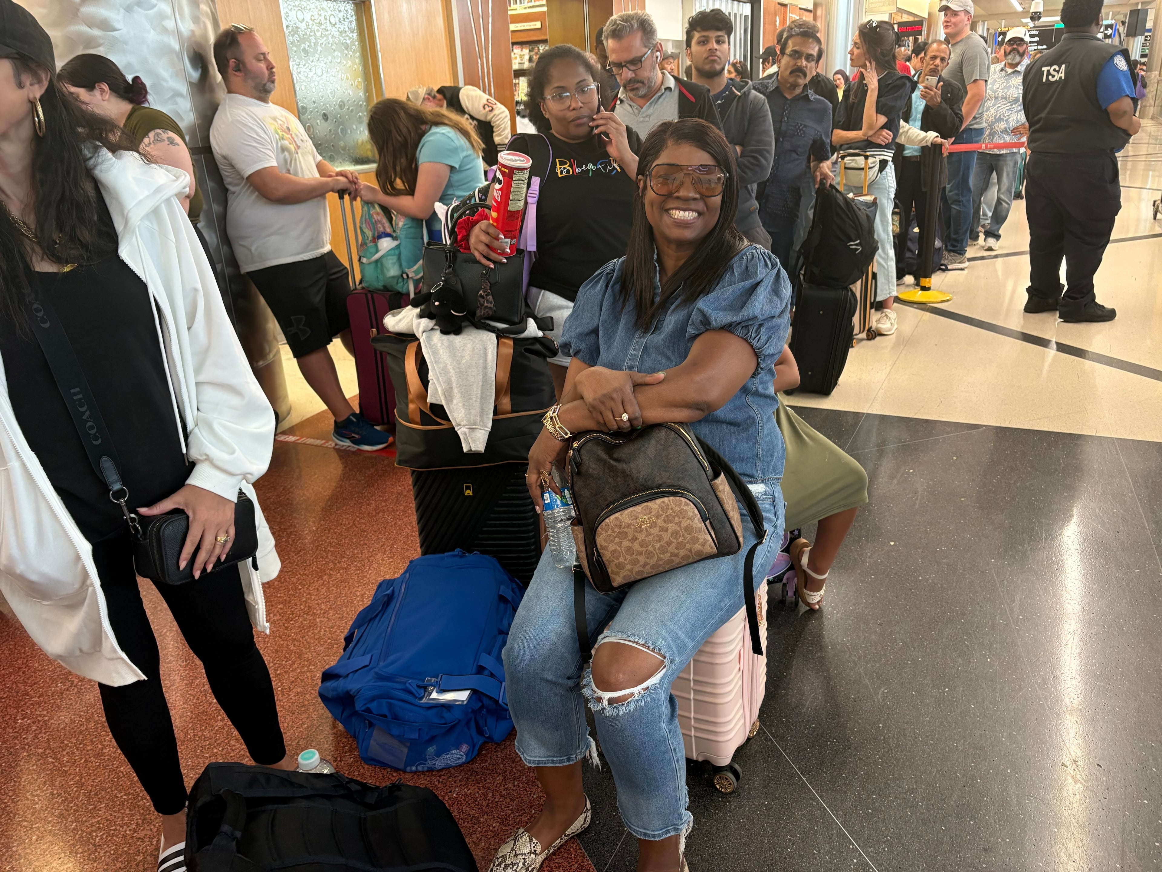 Atlanta airport passenger Troy Lawrence sits on her suitcase Sunday as she waits in the hourslong security line that snaked through the north terminal. Lawrence said she was trying to make back to Omaha, Nebraska to open her childcare facility in the morning.
(Shaddi Abusaid/shaddi.abusaid@ajc.com)
