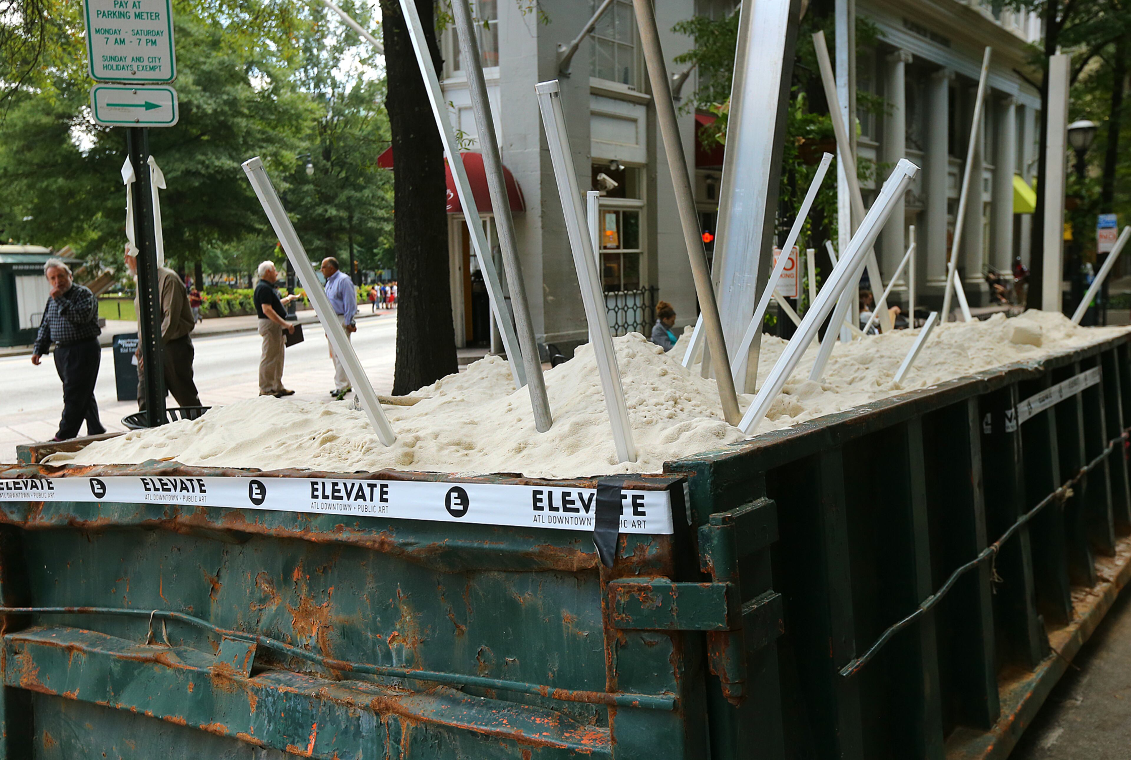 Pedestrians pass by one of 10 dumpsters being transformed into a visual arts environment Monday, Oct. 13, 2014, in Atlanta. 20 artists were given 10 big trash receptacles to create a work of public art that will be part of this year's Elevate, the Office of Cultural Affairs' free week-long public art event from Oct. 17-23. CURTIS COMPTON / CCOMPTON@AJC.COM