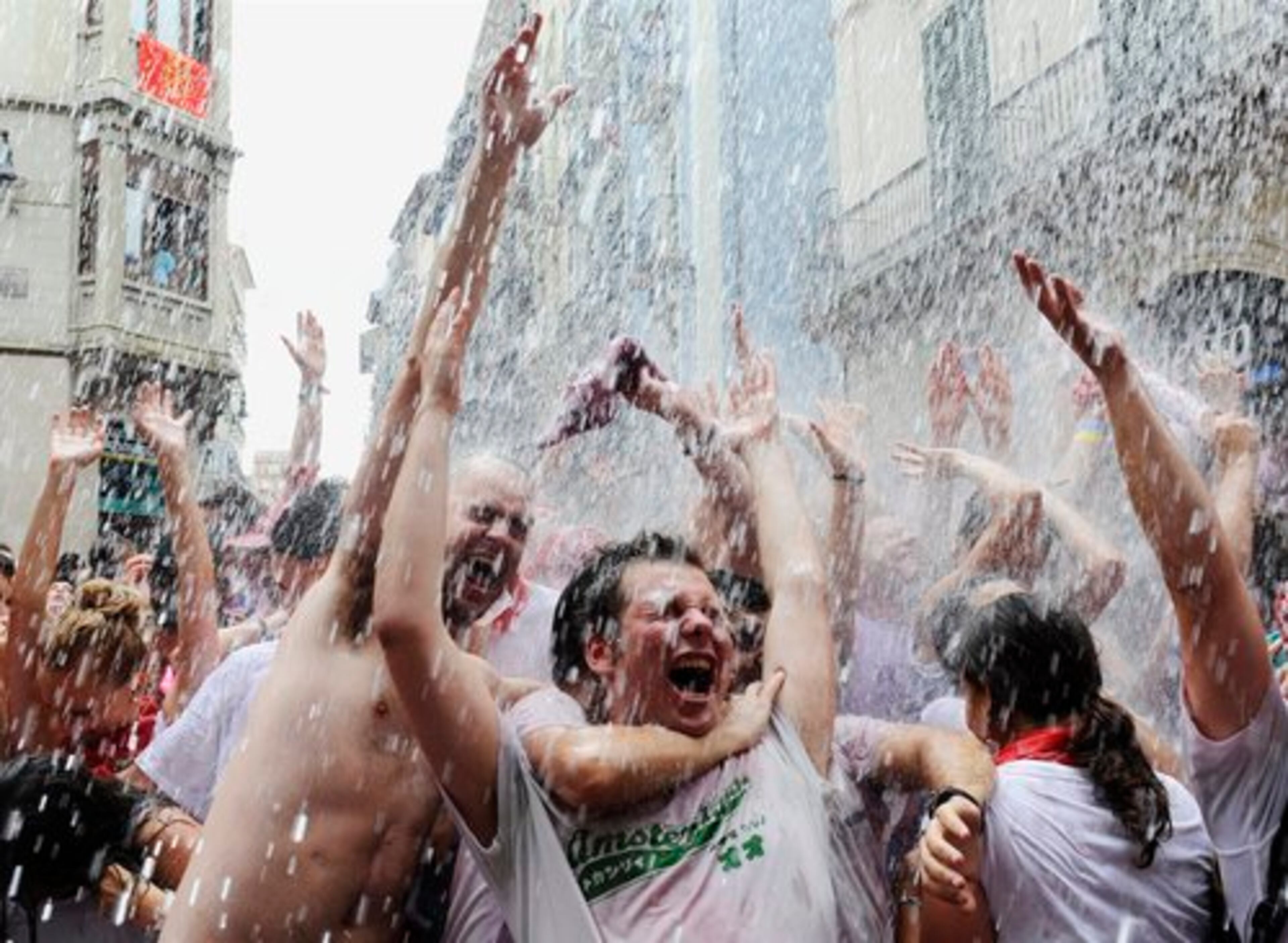 Revelers react as water is thrown from a balcony during the 'Chupinazo', the official opening of the San Fermin fiestas.