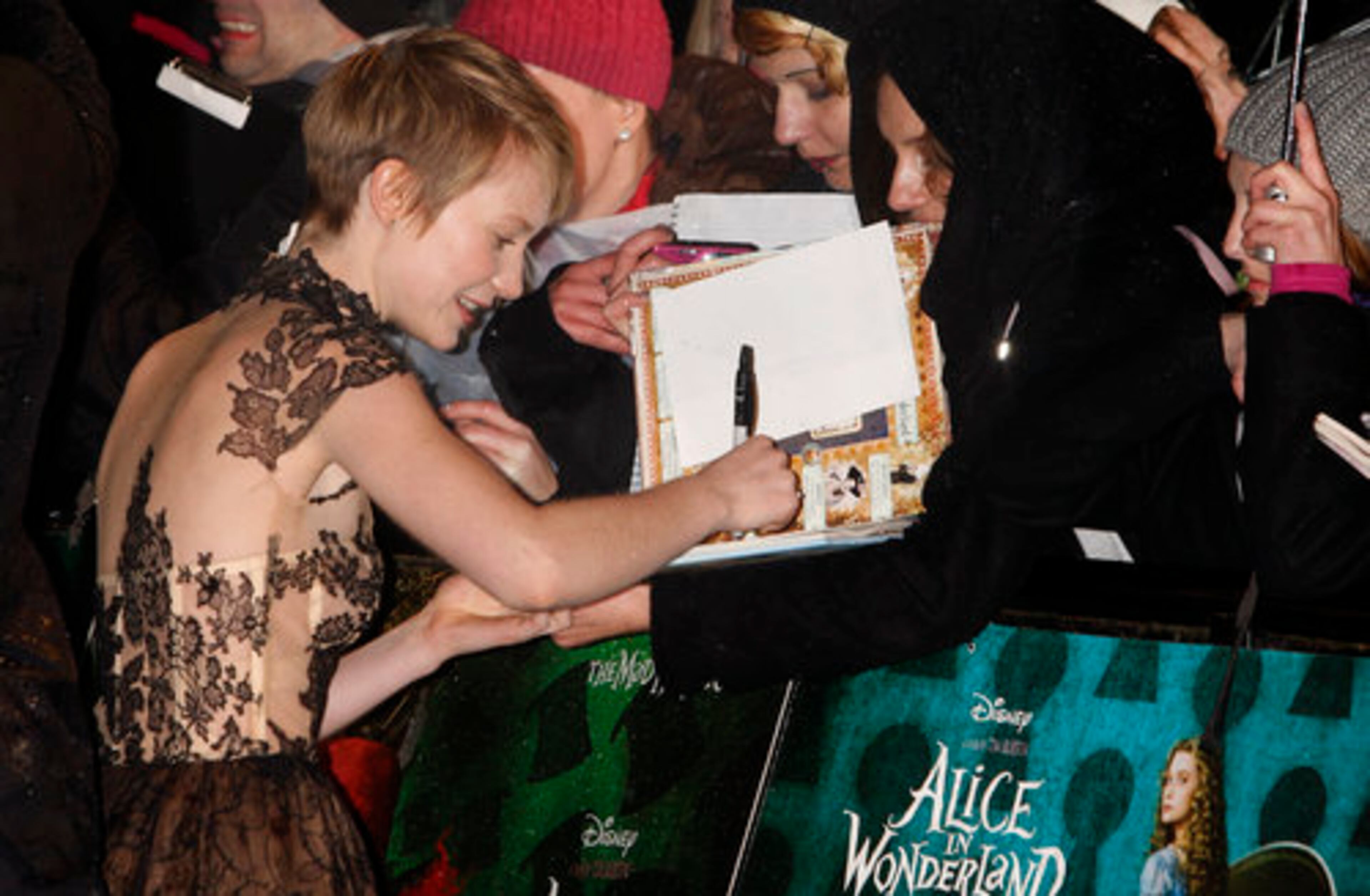 Australian actress Mia Wasikowska, left, signs autographs.