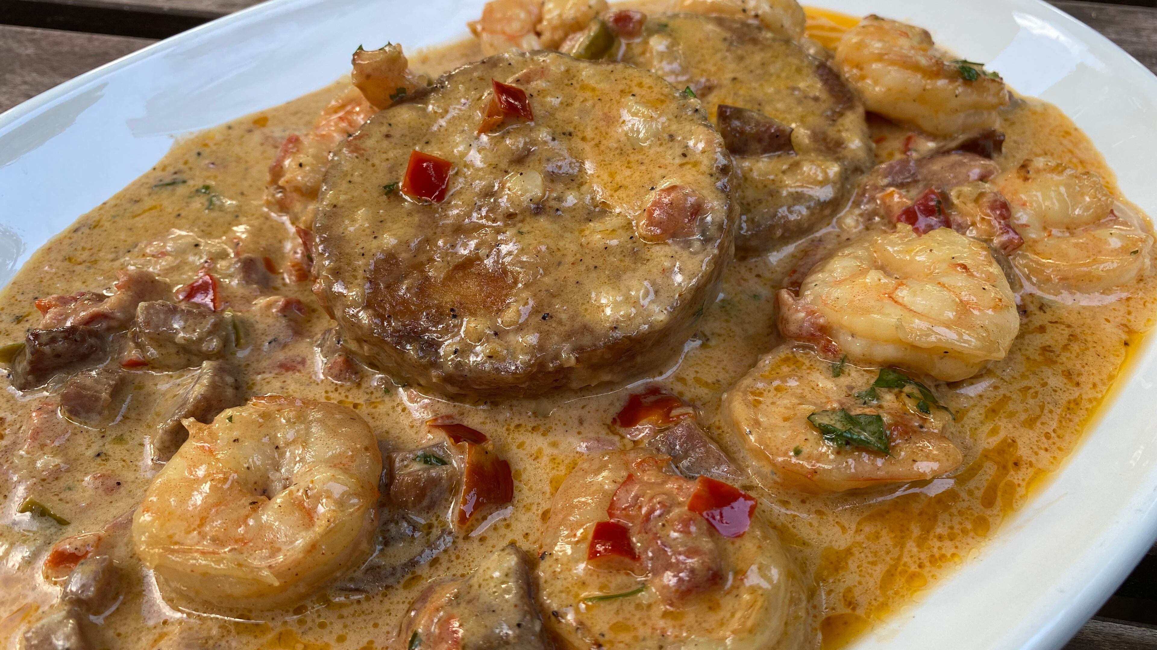 Bayou’Q features sauteed shrimp in Cajun gravy, dotted with smoked tasso ham and andouille sausage, over cheesy grits cakes. Ligaya Figueras/ligaya.figueras@ajc.com.