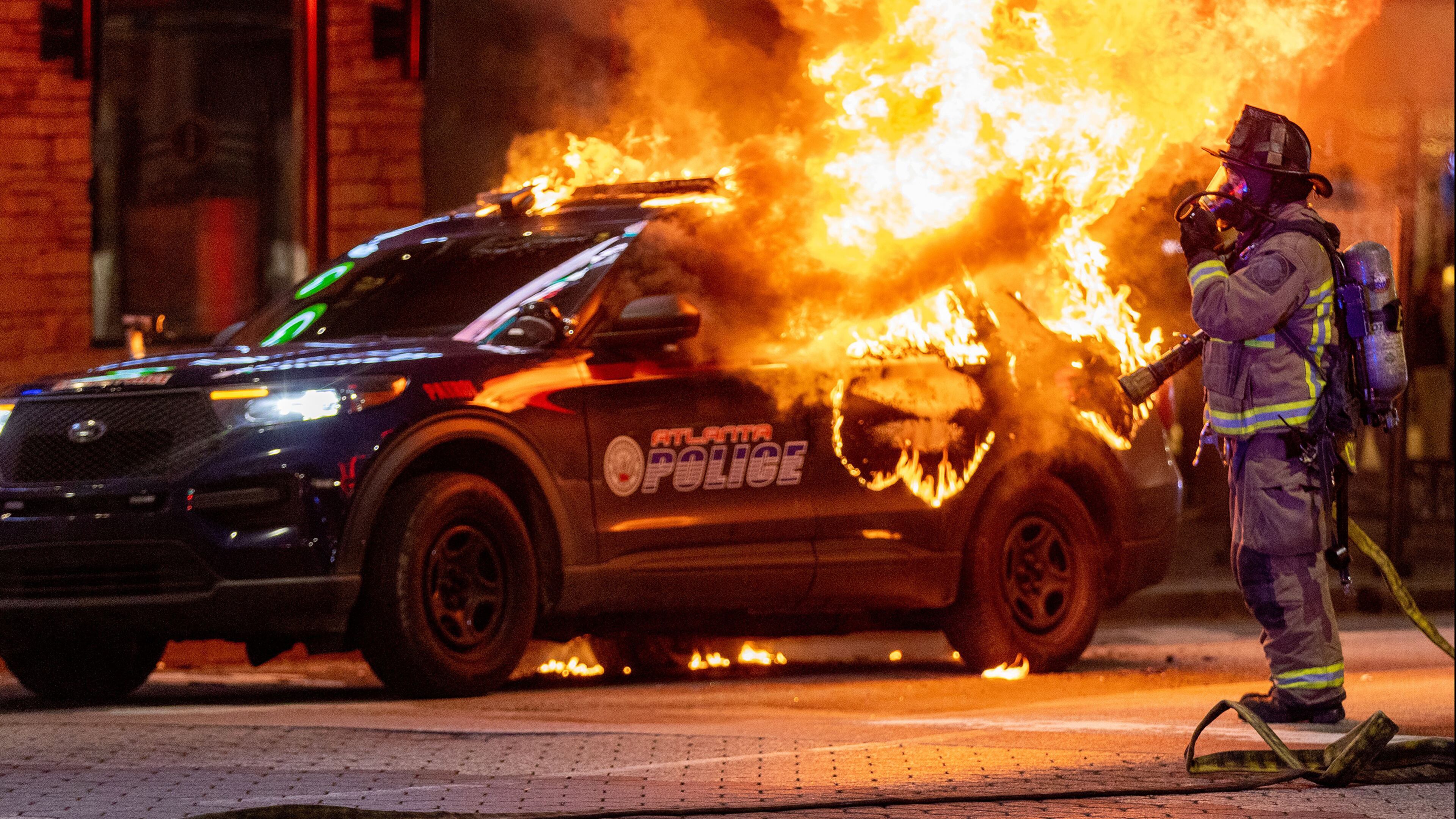 Atlanta firefighters prepared to extinguish a police car that was set on fire during a protest in Atlanta on Saturday. The Atlanta Police Department said several arrests had been made. (Steve Schaefer/The Atlanta Journal-Constitution/TNS)