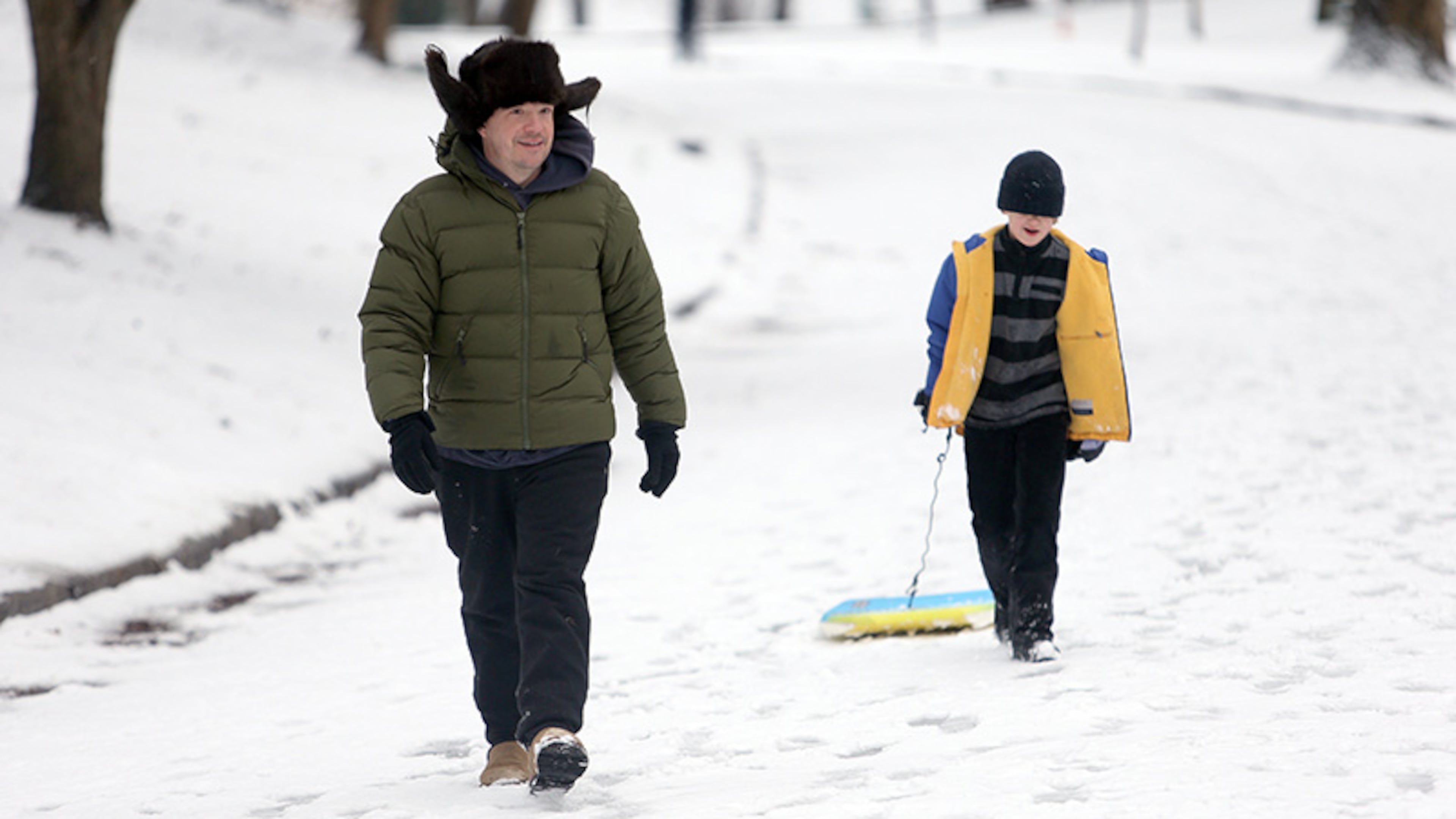 John Brewster and his daughter Sarah, 8, head to another hill while sledding on a boogie board in Grant Park on Thursday morning. Students across Atlanta would have another day to frolick in the melting snow with classes out on Friday.