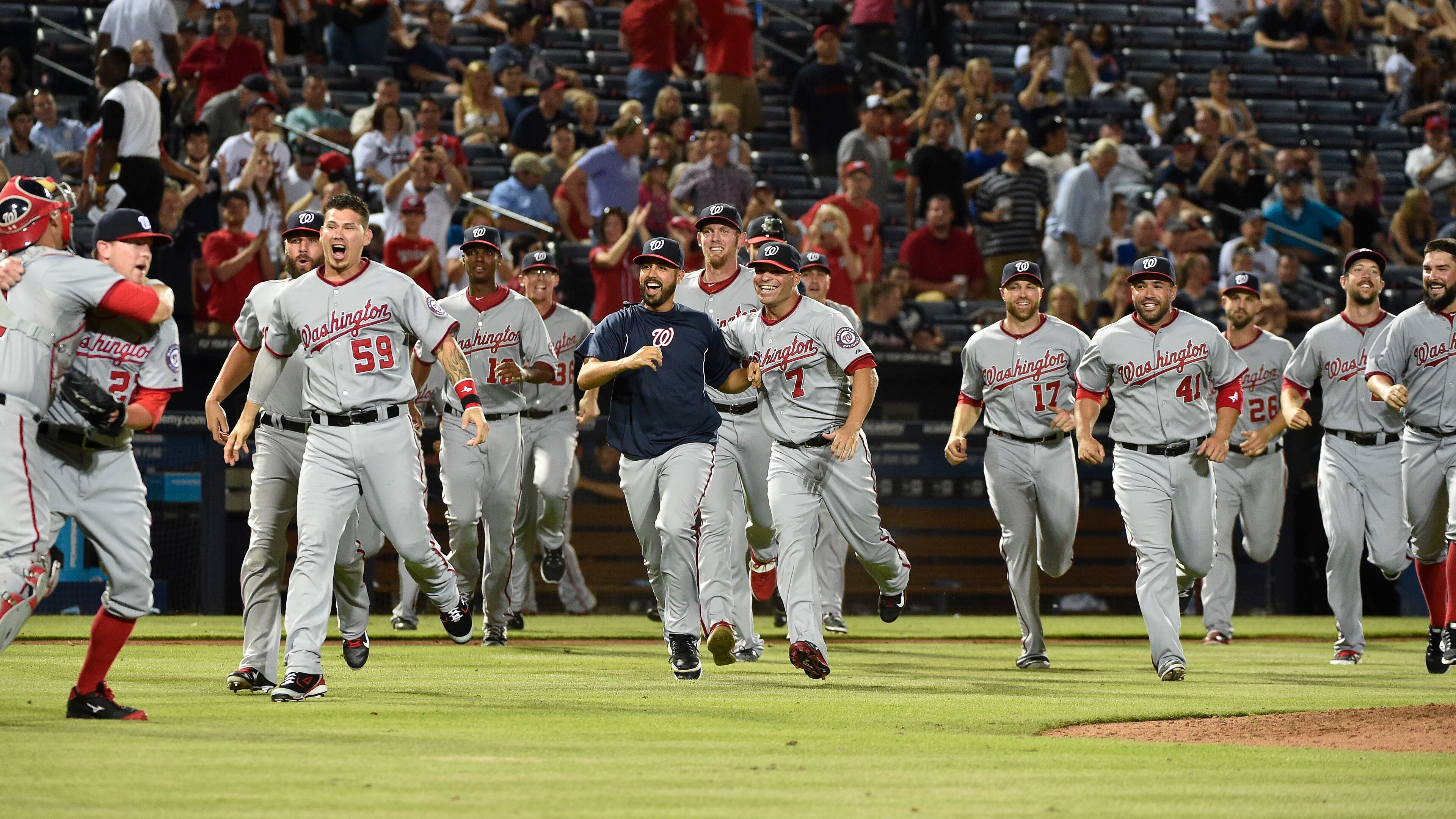 Washington Nationals teammates run out onto the field to congratulate pitcher Drew Storen (22) and catcher Wilson Ramos after clinching the NL East division against the Atlanta Braves in a baseball game Tuesday, Sept. 16, 2014, in Atlanta. Washington won 3-0. (AP Photo/David Tulis) Nationals became 11th team to celebrate something on Braves' field since 1992.