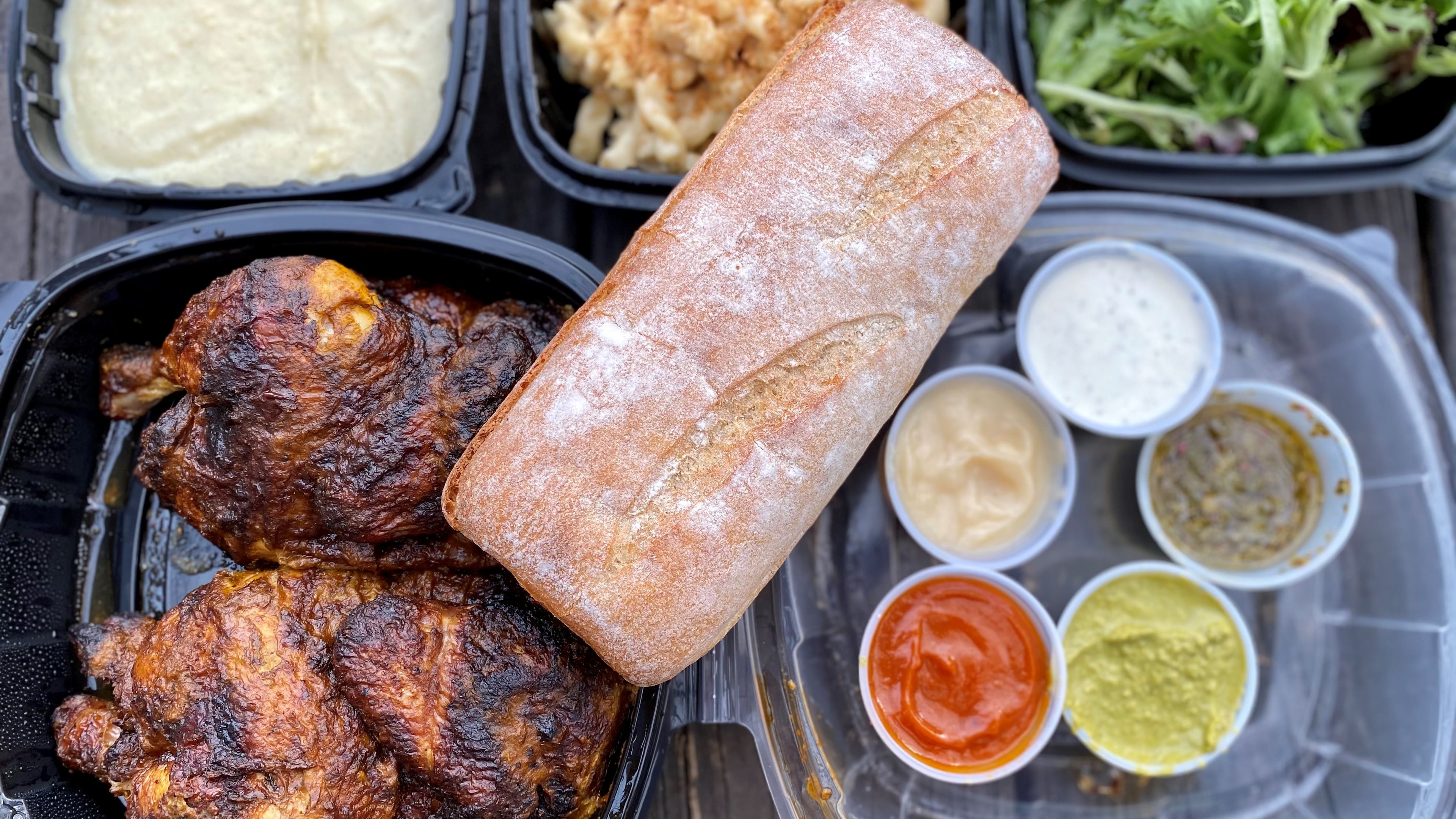 This takeout order from Fire Hen includes a whole chicken with French bread, dipping sauces, and sides (mashed potatoes, fondu mac and cheese and mixed green salad). Wendell Brock for The Atlanta Journal-Constitution