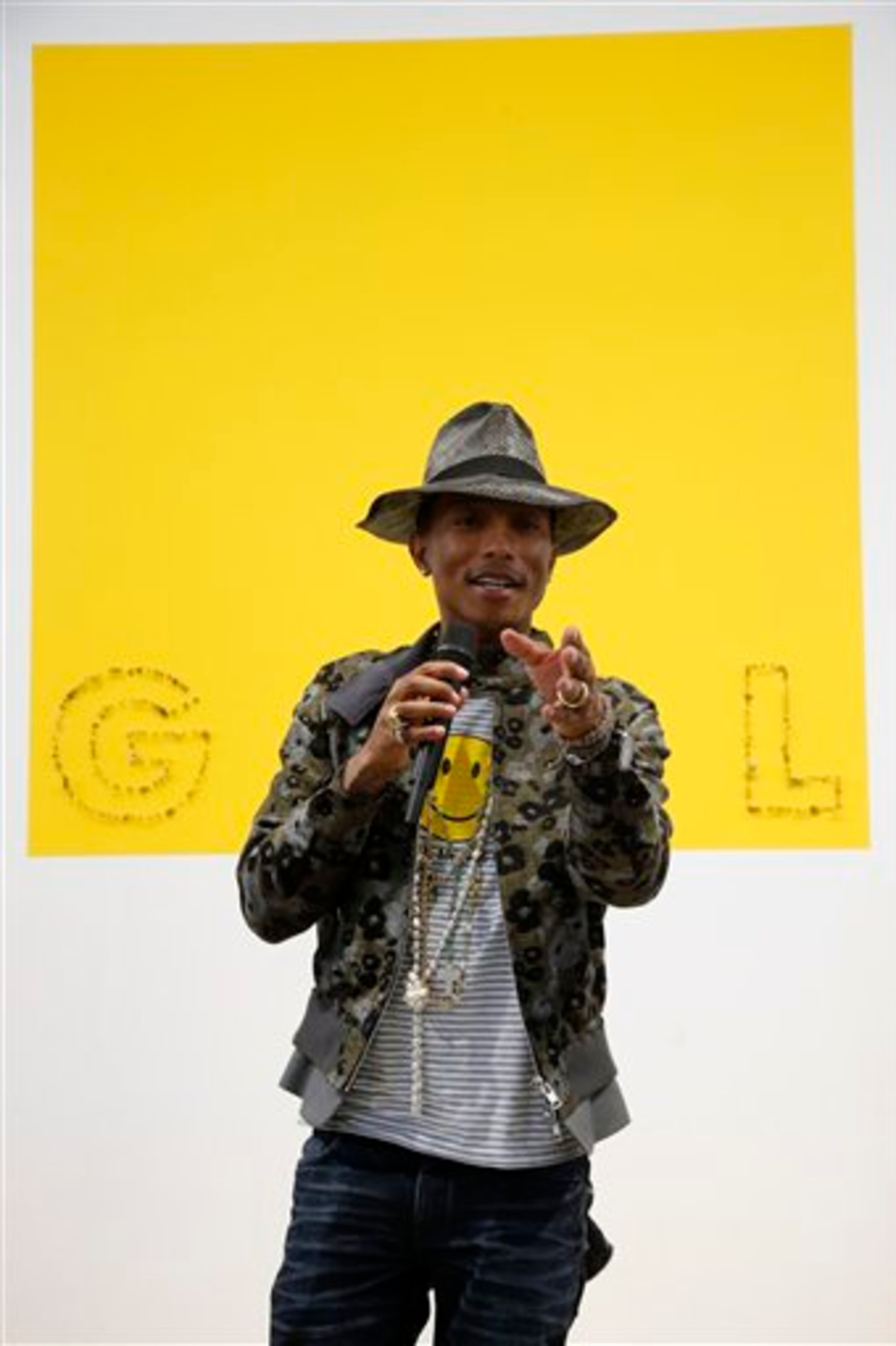 Singer Pharrell Williams poses during a news conference for the exhibition "GIRL" at the Perrotin Gallery in Paris, Monday, May 26, 2014. Williams curated an exhibition encompassing around 40 art pieces, presenting their visions of femininity, muses, female creativity and freedom. The show opens on May 27 and runs through June 27, 2014. The piece behind Williams is "GIRL" by French artist Guy Limone. (AP Photo/Francois Mori)