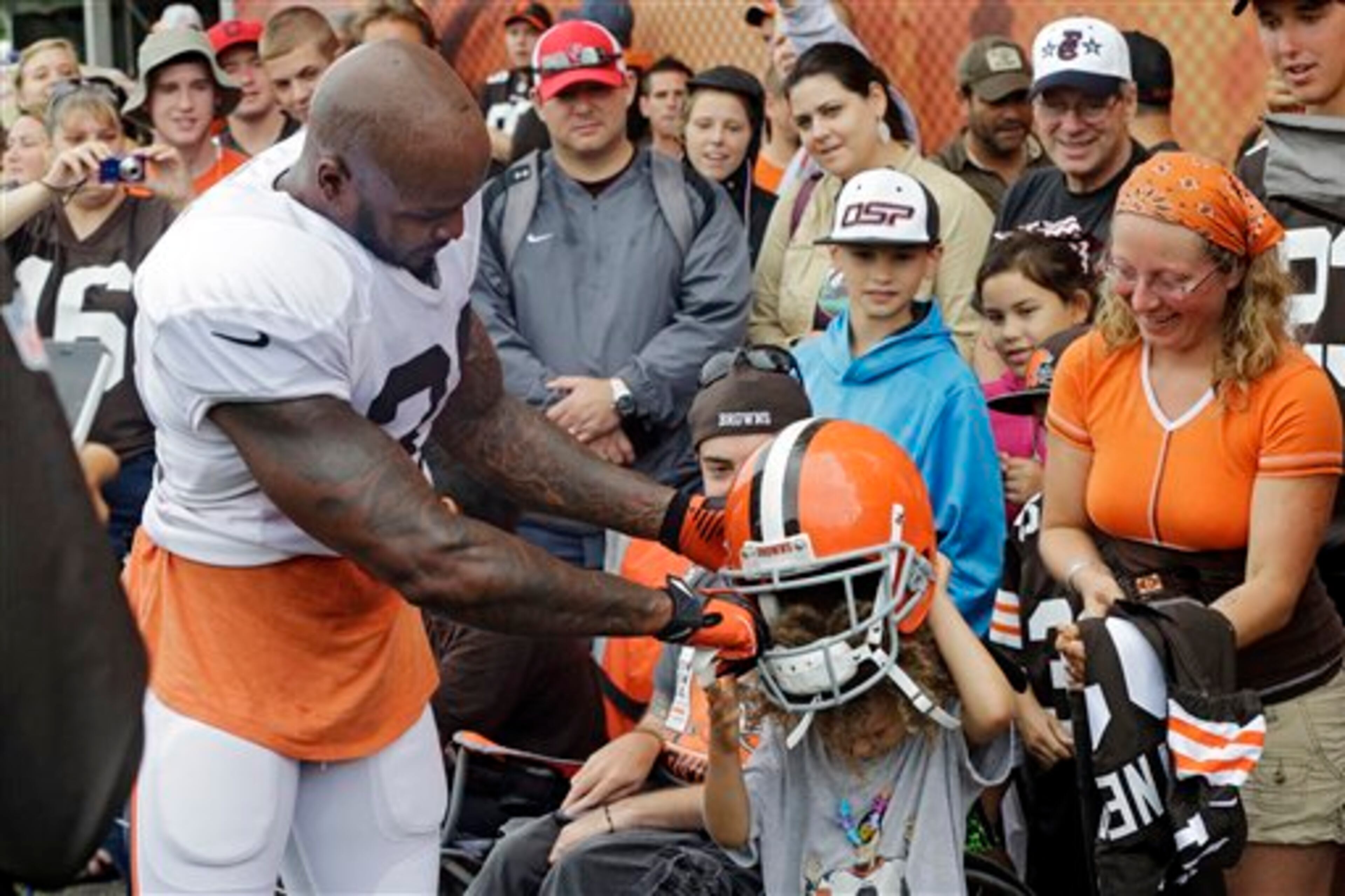 Cleveland Browns defensive back Donte Whitner, left, lets a young fan try on his helmet during practice at NFL football training camp in Berea, Ohio Monday, Aug. 11, 2014. (AP Photo/Mark Duncan)