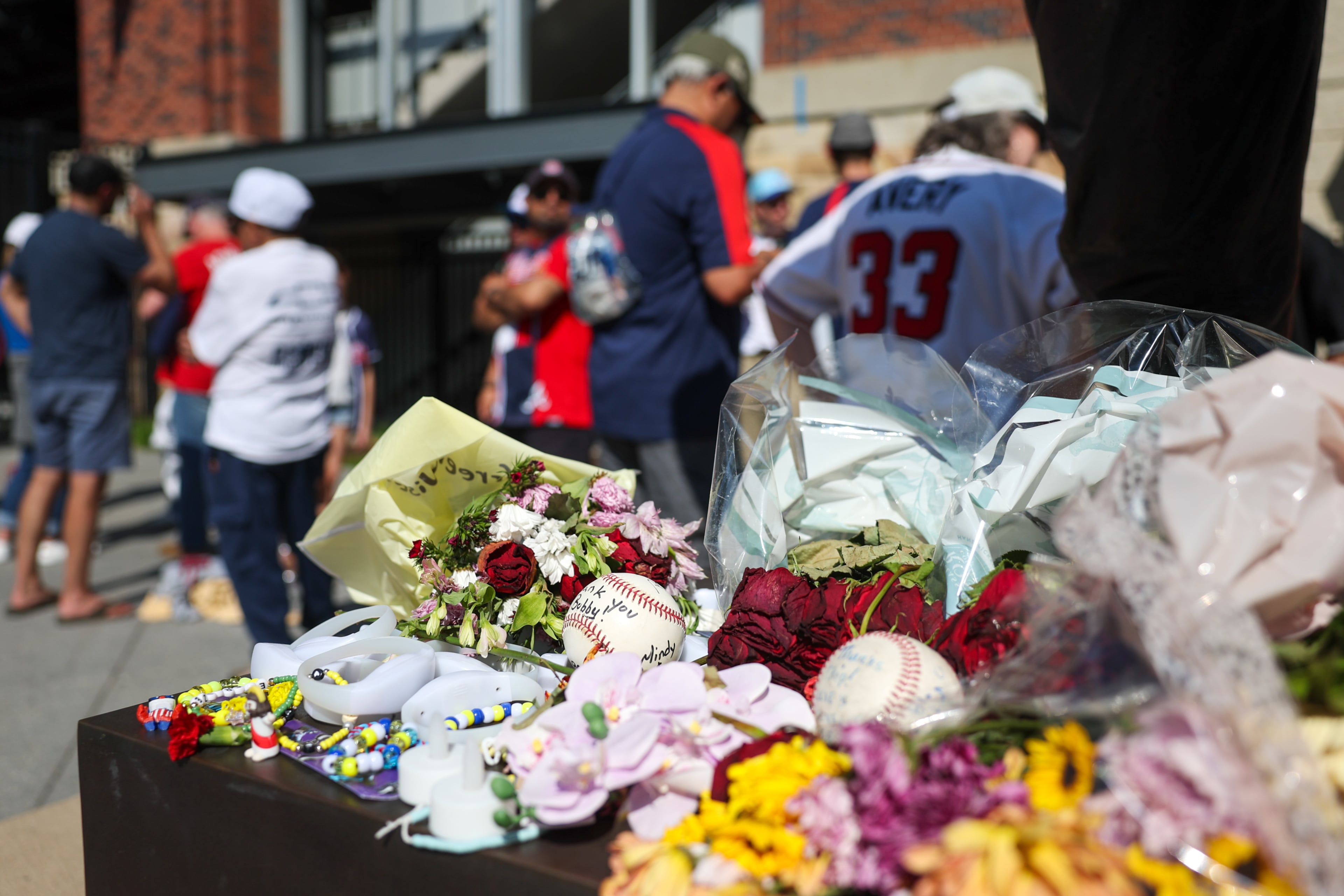 Fans left flowers and other items for the late legendary Braves manager Bobby Cox by his statue at Truist Park in Atlanta on May 12, 2026. Cox died at age 84 on Saturday May, 9. (Arvin Temkar/AJC)