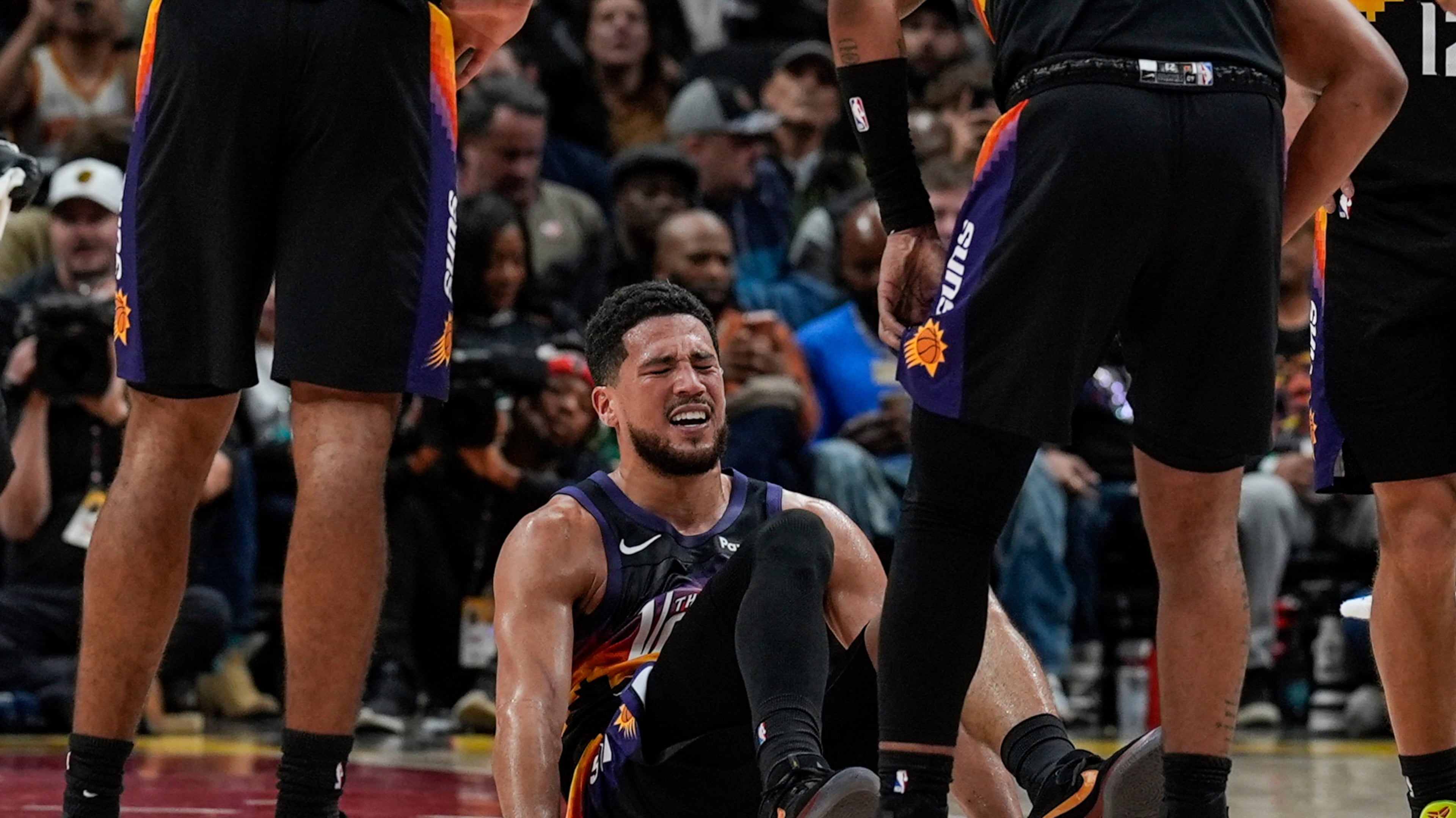 Phoenix Suns guard Devin Booker (1) winces in pain during the second half of an NBA basketball game against the Atlanta Hawks, Friday, Jan. 23, 2026, in Atlanta. (AP Photo/Mike Stewart)