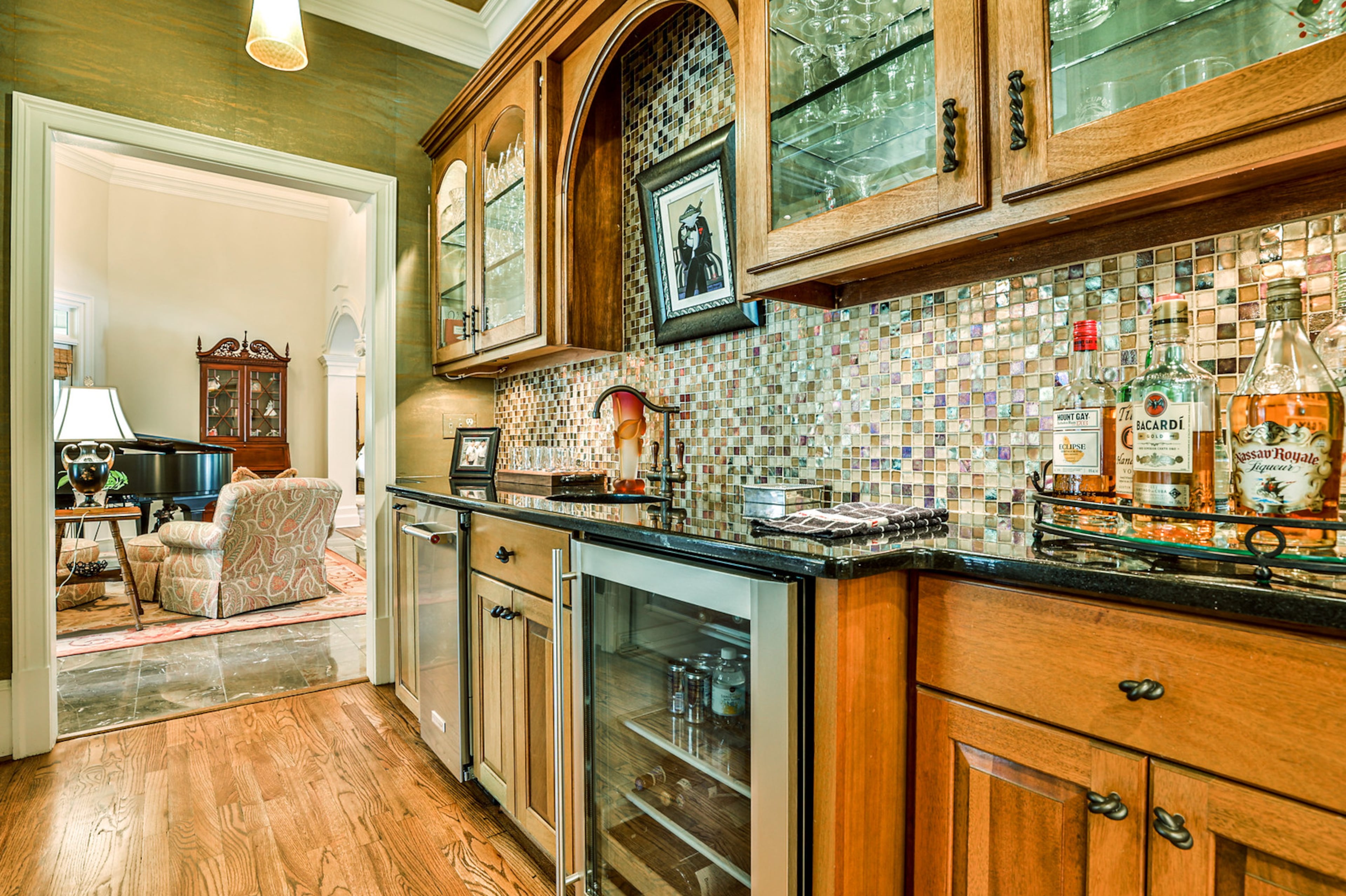 Custom wet bar offers a new Kitchen Aid ice maker, beverage/wine cooler, Mahogany cabinets with multi-colored tile backsplash. Text by Jan Hart