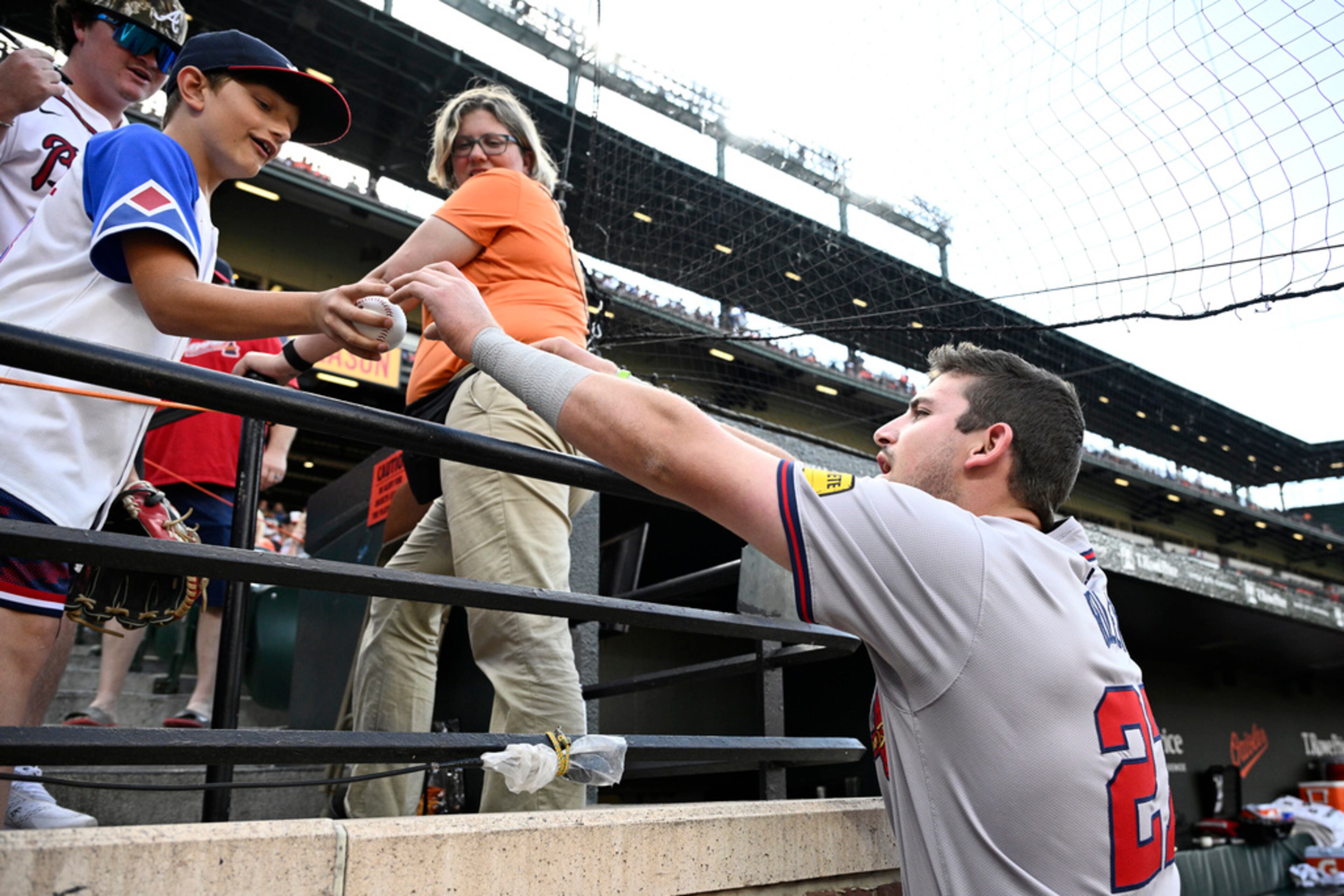 Atlanta Braves third baseman Austin Riley, right, gives a baseball to a fan after signing it before the team's game against the Baltimore Orioles, Wednesday, June 12, 2024, in Baltimore. (AP Photo/Nick Wass)