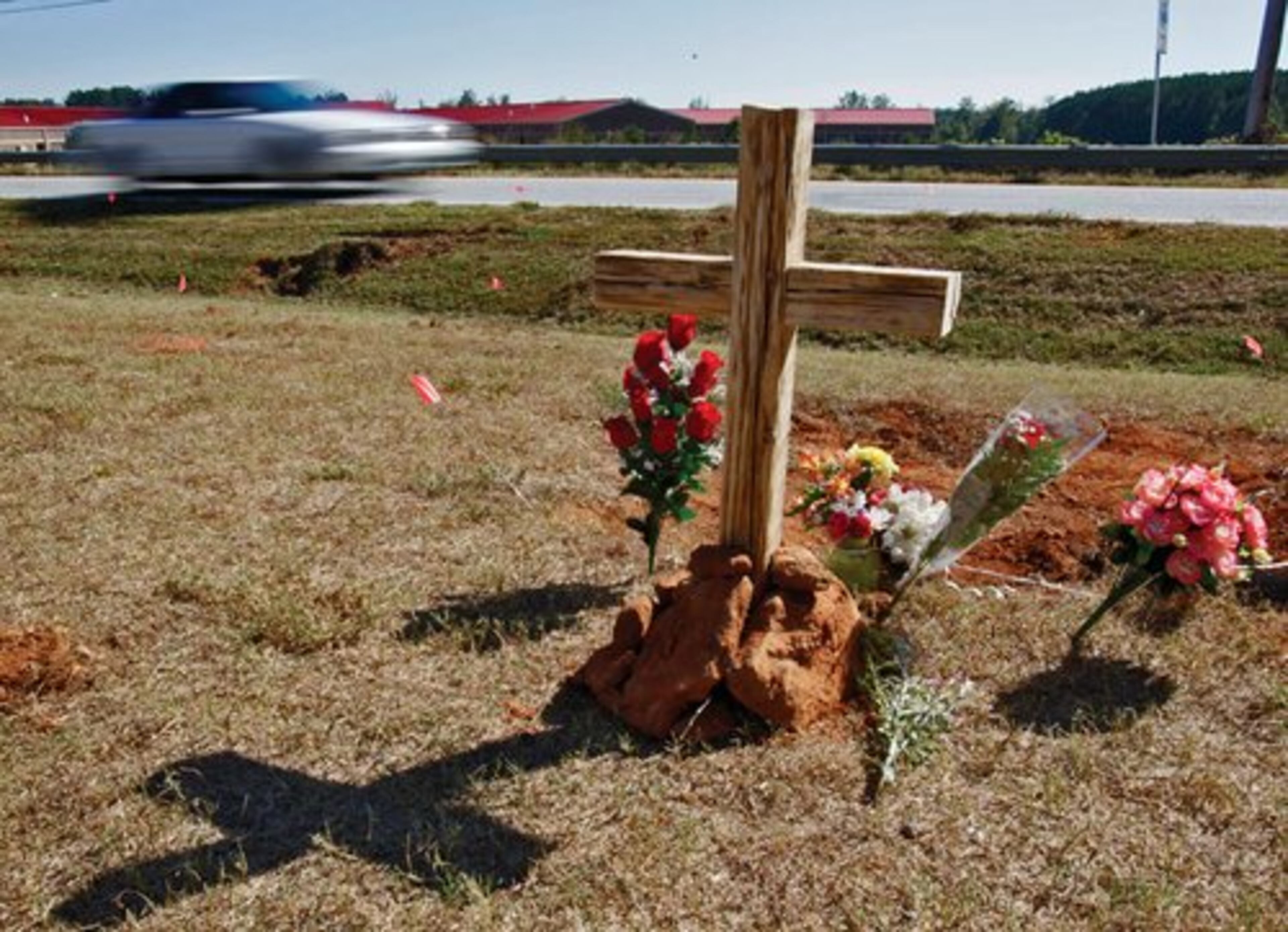 A wooden cross, two tiki torches and bouquets of flowers marked the spot where a bus from Temple High School, on its way to a nearby vocational school, went off the right side of Highway 113, across a driveway, into a culvert and then into a ditch. The crash killed James Rashawn Walker, 17, who played on Temple High's football team, and injured 13 others.