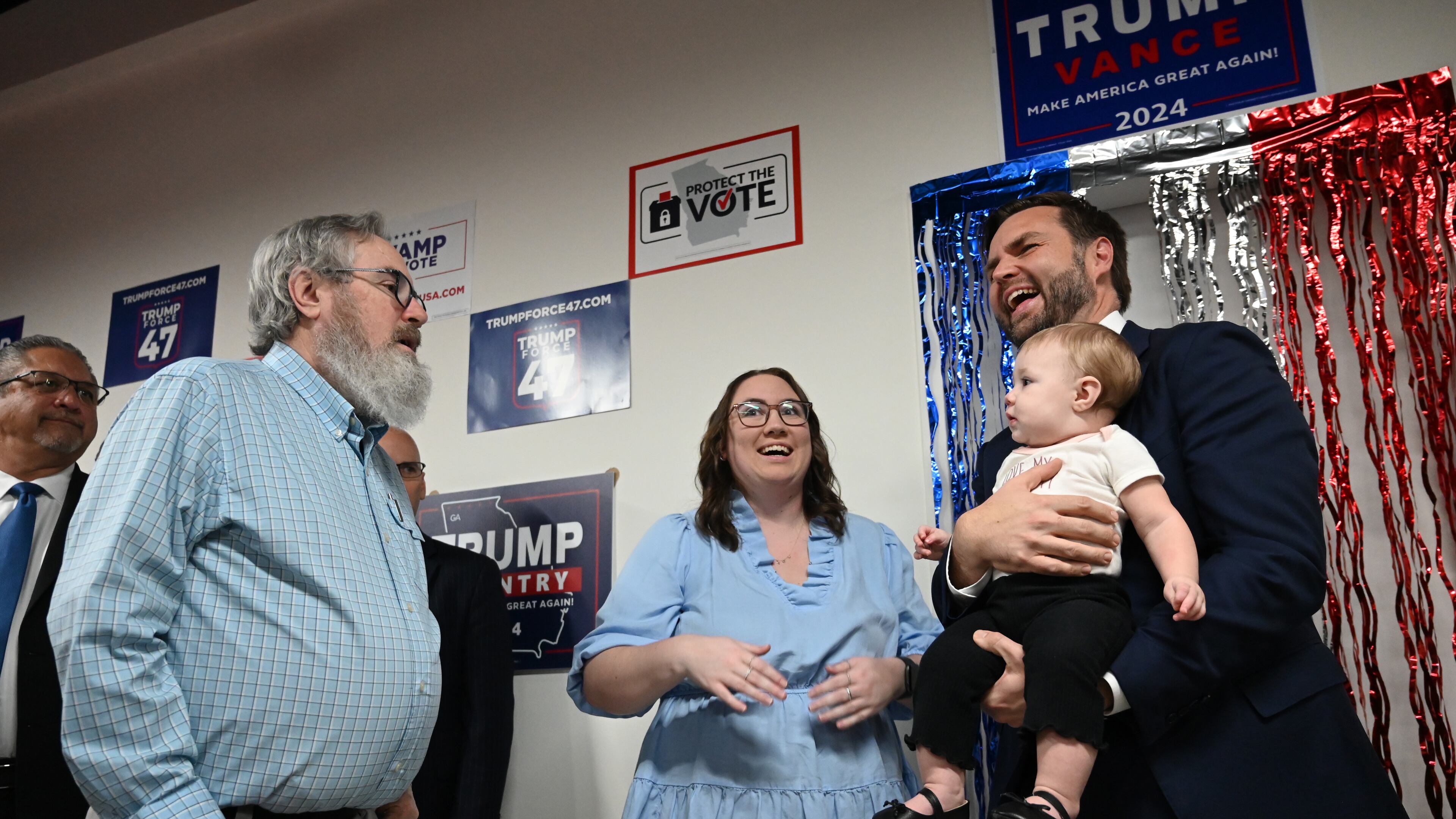 Republican vice presidential nominee JD Vance holds 10-month-old Emmalynn as her grandfather David Lowry (left) and mother Daelen Lowry (center) react. Vance was visiting the Trump campaign's Gwinnett County field office, Friday, October 11, 2024, in Lawrenceville. (Hyosub Shin / AJC)