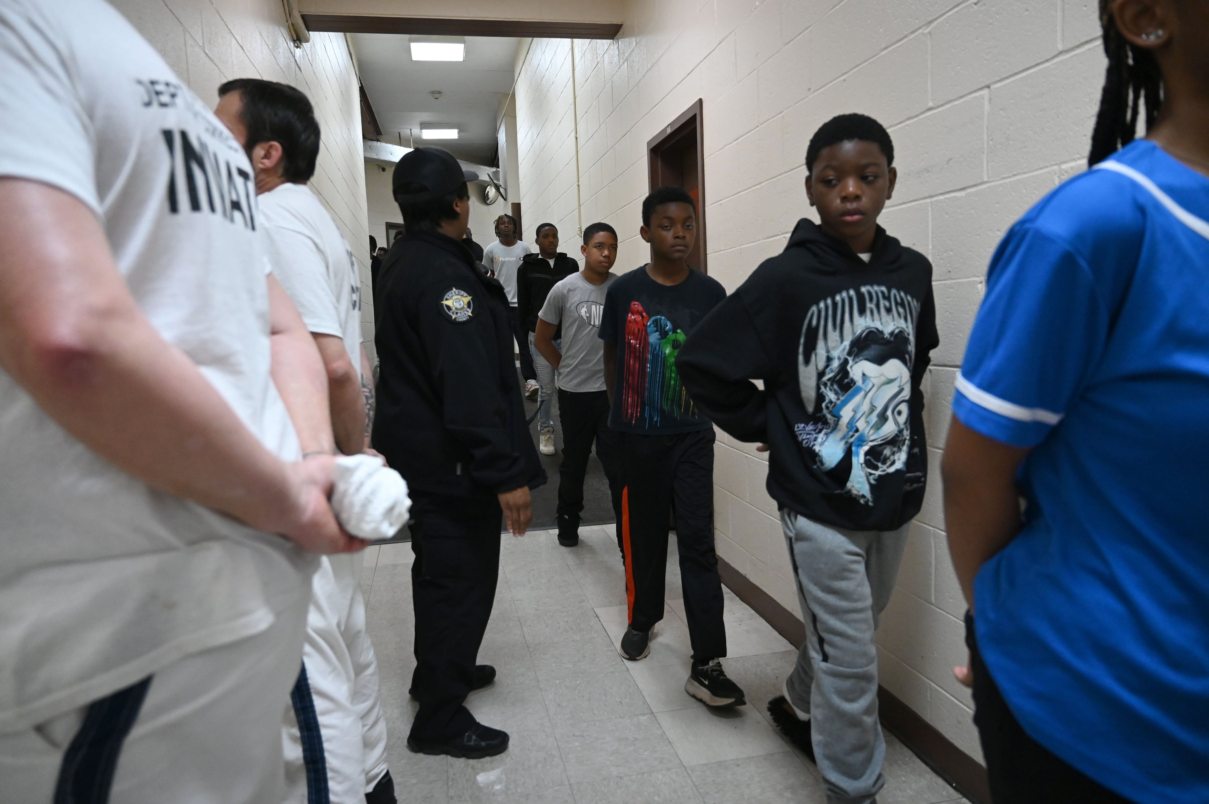 Students, with their hands behind their backs, react as they encounter inmates while walking down the hallway during a visit to the Athens-Clarke County Correctional Institution as part of a program that aims to curb youth crime and violence. (Hyosub Shin/AJC)