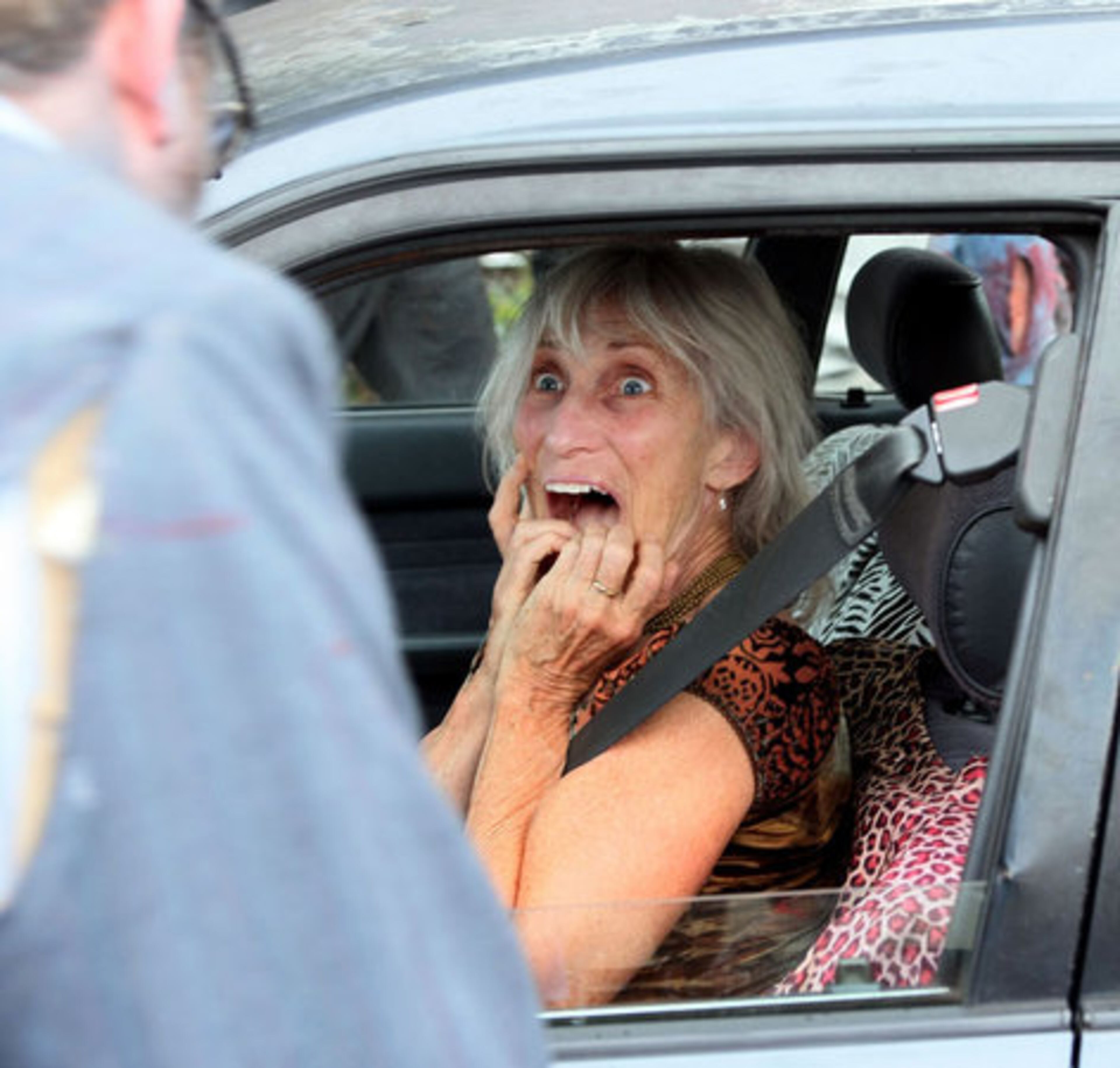 Jane Merkle pretends to be terrified as costumed zombies pass by her car sitting on Decatur street.
