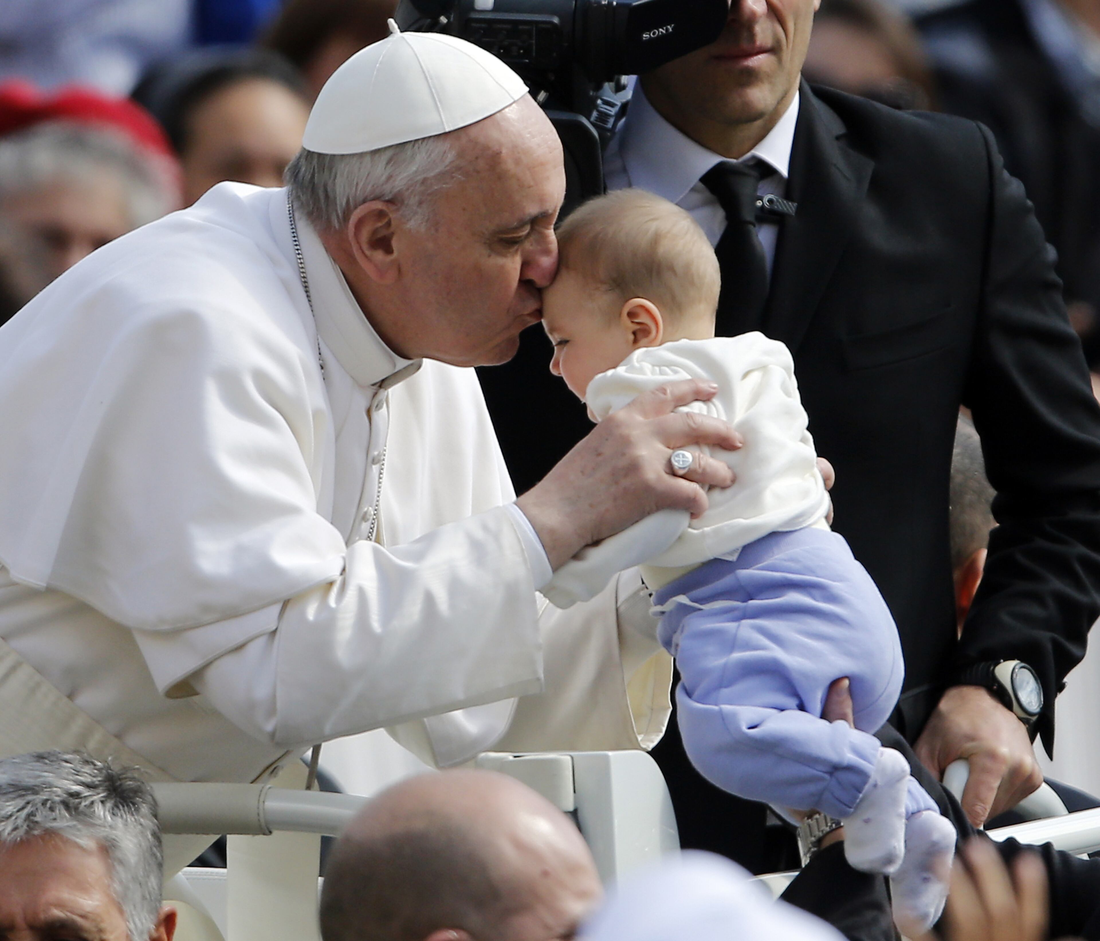 Pope Francis kisses a baby handed to him as he is driven through the crowd during his general audience, in St. Peter's Square, at the Vatican, Wednesday, March 27, 2013. (AP Photo/Andrew Medichini)