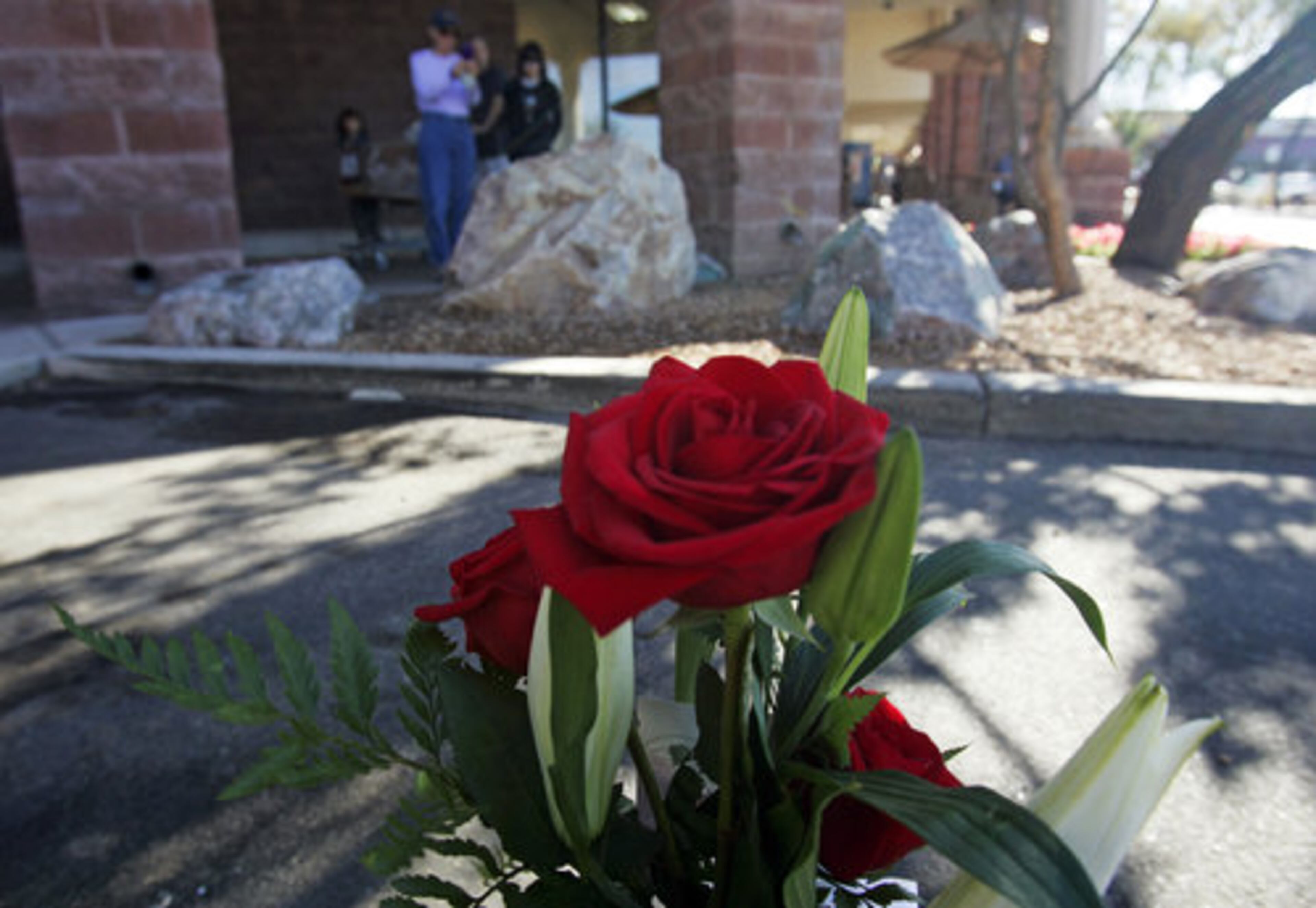 People gaze at a small memorial plaque on a rock at the Safeway market on Saturday, Jan. 7, 2012, to commemorate the victims of the mass shooting on Jan. 8, 2011, in Tucson. Arizona is marking the event with a series of events, including community-wide bell-ringing at the moment of the attack, speeches on behalf of the victims, and an evening candlelight vigil that Giffords will attend.