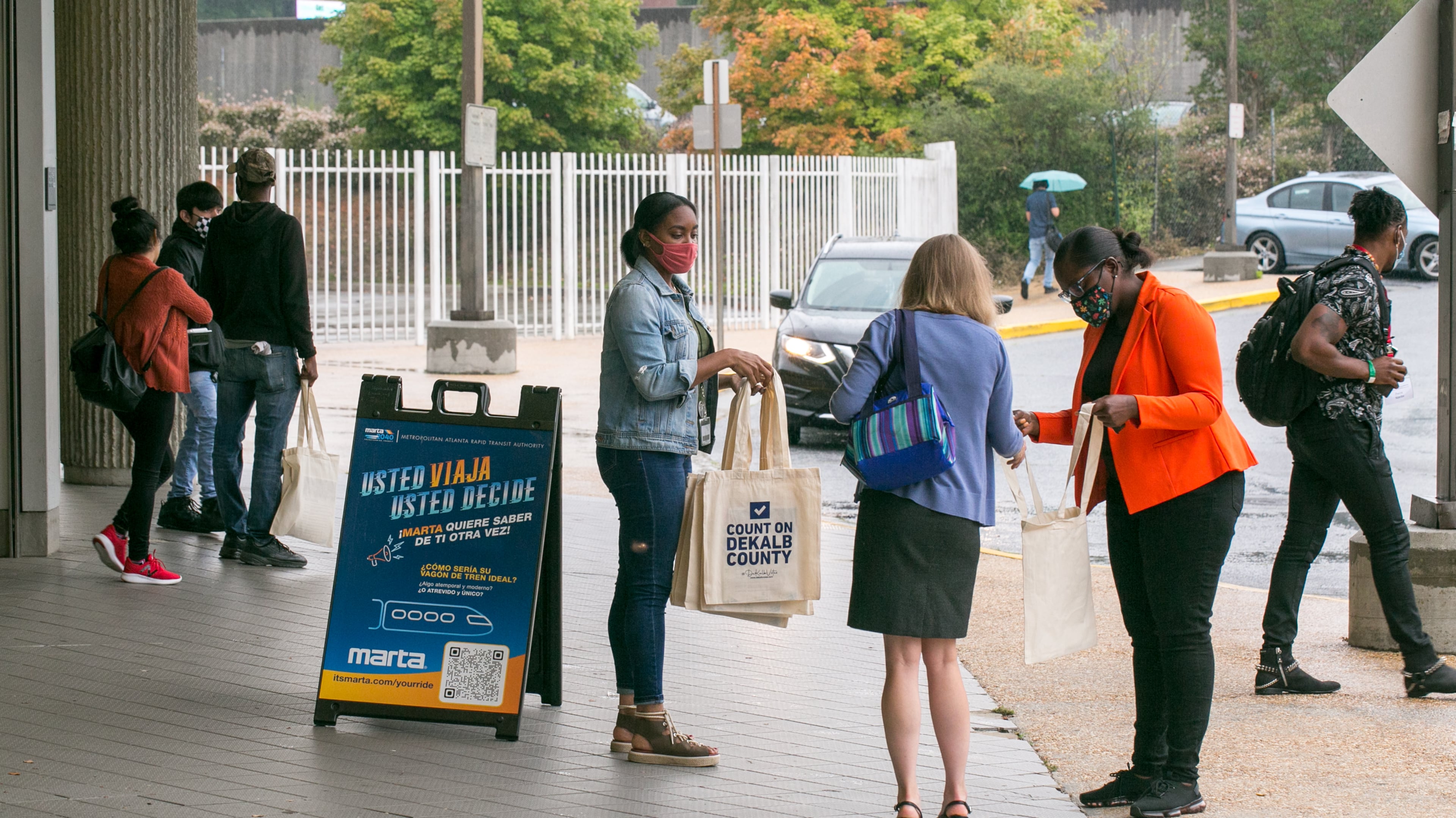 DeKalb County Election officials including Lamashia Davis, center, and Erin Austin, right, in orange, work to spread information about changes in voter laws and offer free voter IDs, if needed, on Wednesday, Sept 15, 2021 at the Chamblee MARTA Station. (Jenni Girtman for The Atlanta Journal-Constitution)