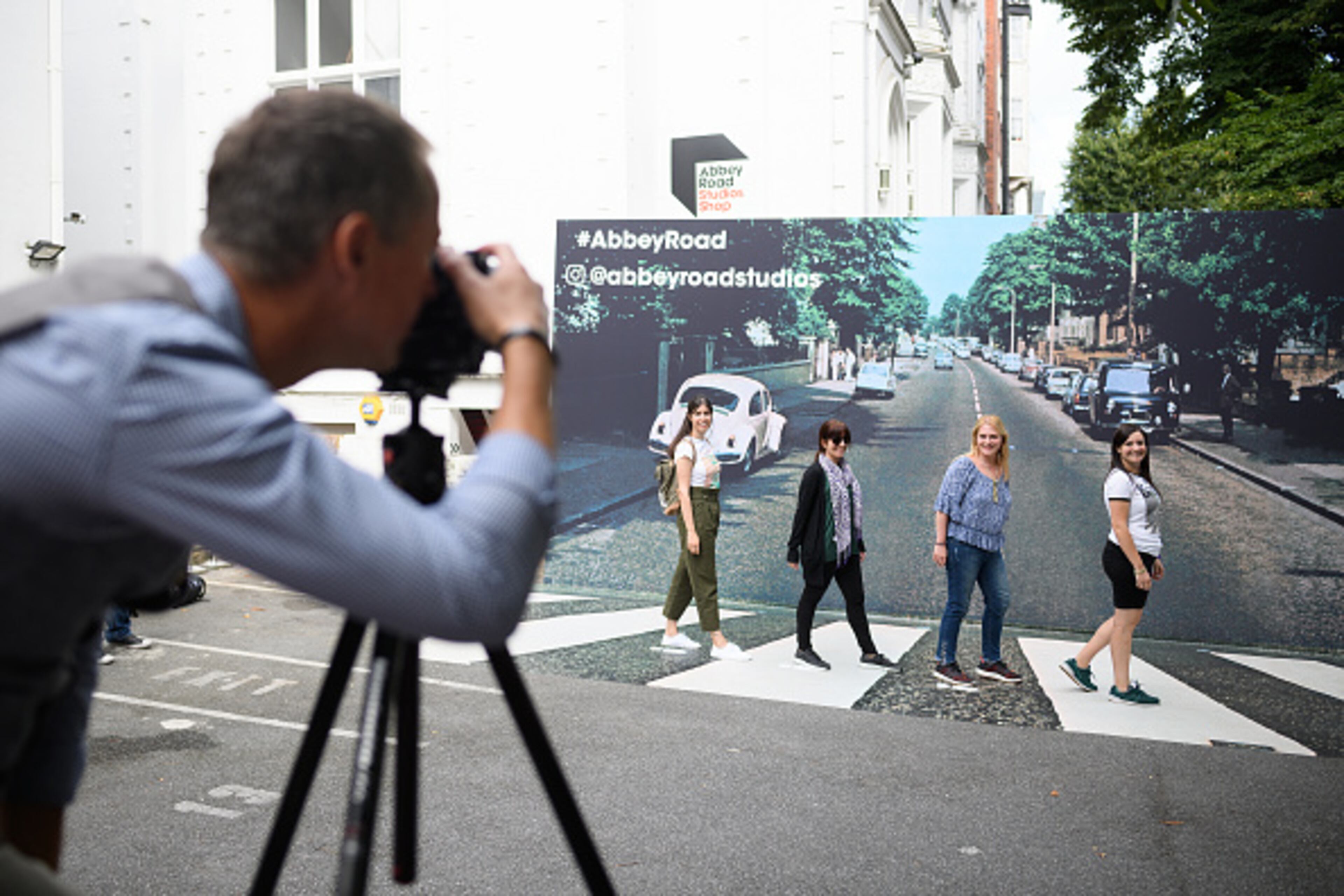 LONDON, ENGLAND - AUGUST 08: Fans pose against a recreation of the pedestrian crossing outside Abbey Road studios, fifty years since the iconic album cover for "Abbey Road" by the Beatles was taken, on August 08, 2019 in London, England. The zebra crossing is just outside the recording studios and has become a popular location for music fans visiting London. (Photo by Leon Neal/Getty Images)