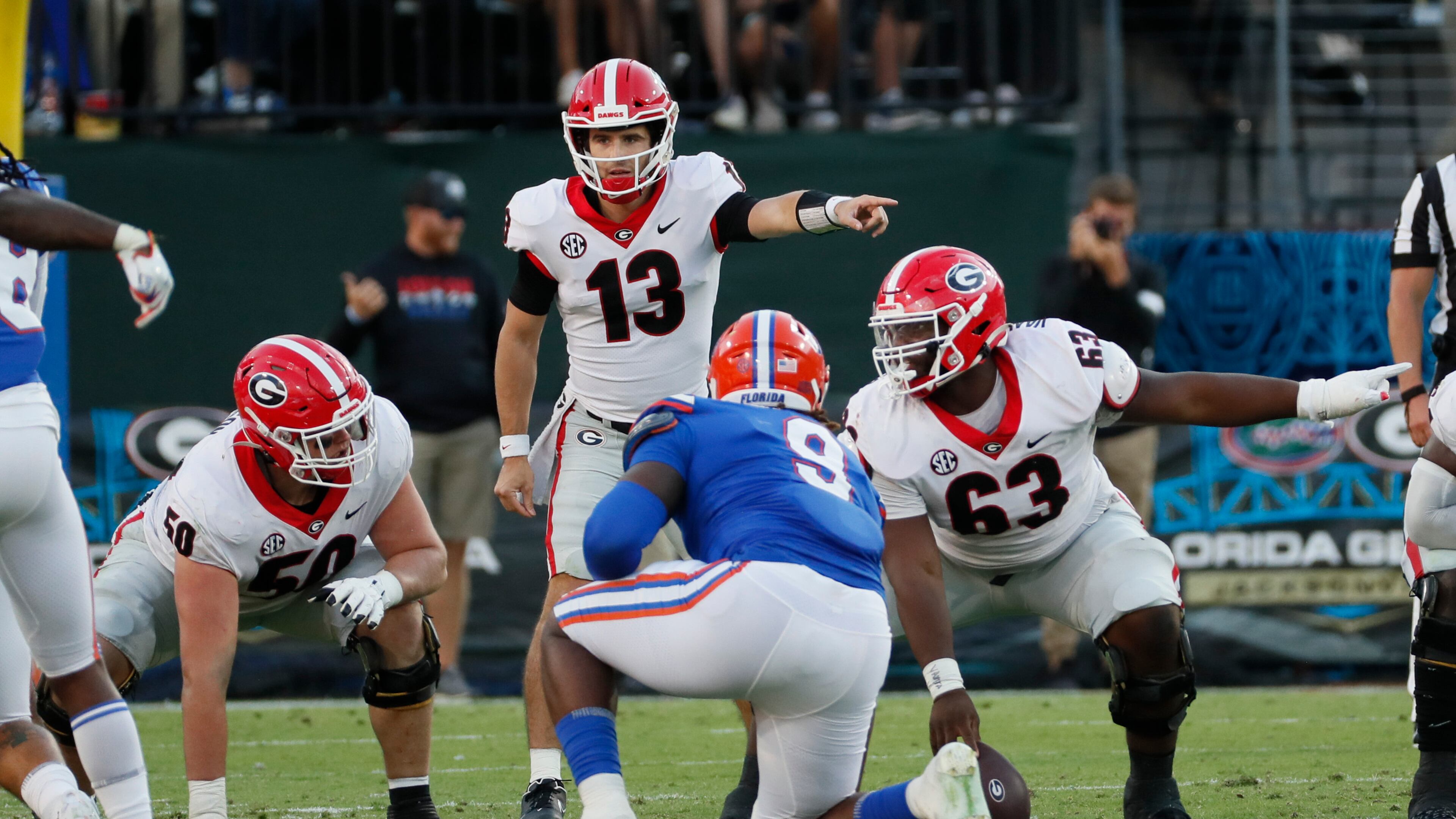 10/30/21 - Jacksonville - Georgia Bulldogs quarterback Stetson Bennett (13) directs the offense with Georgia Bulldogs offensive lineman Warren Ericson (50) and Georgia Bulldogs offensive lineman Sedrick Van Pran (63) during the second half of the annual NCCA Georgia vs Florida game at TIAA Bank Field in Jacksonville. Georgia won 34-7. Bob Andres / bandres@ajc.com