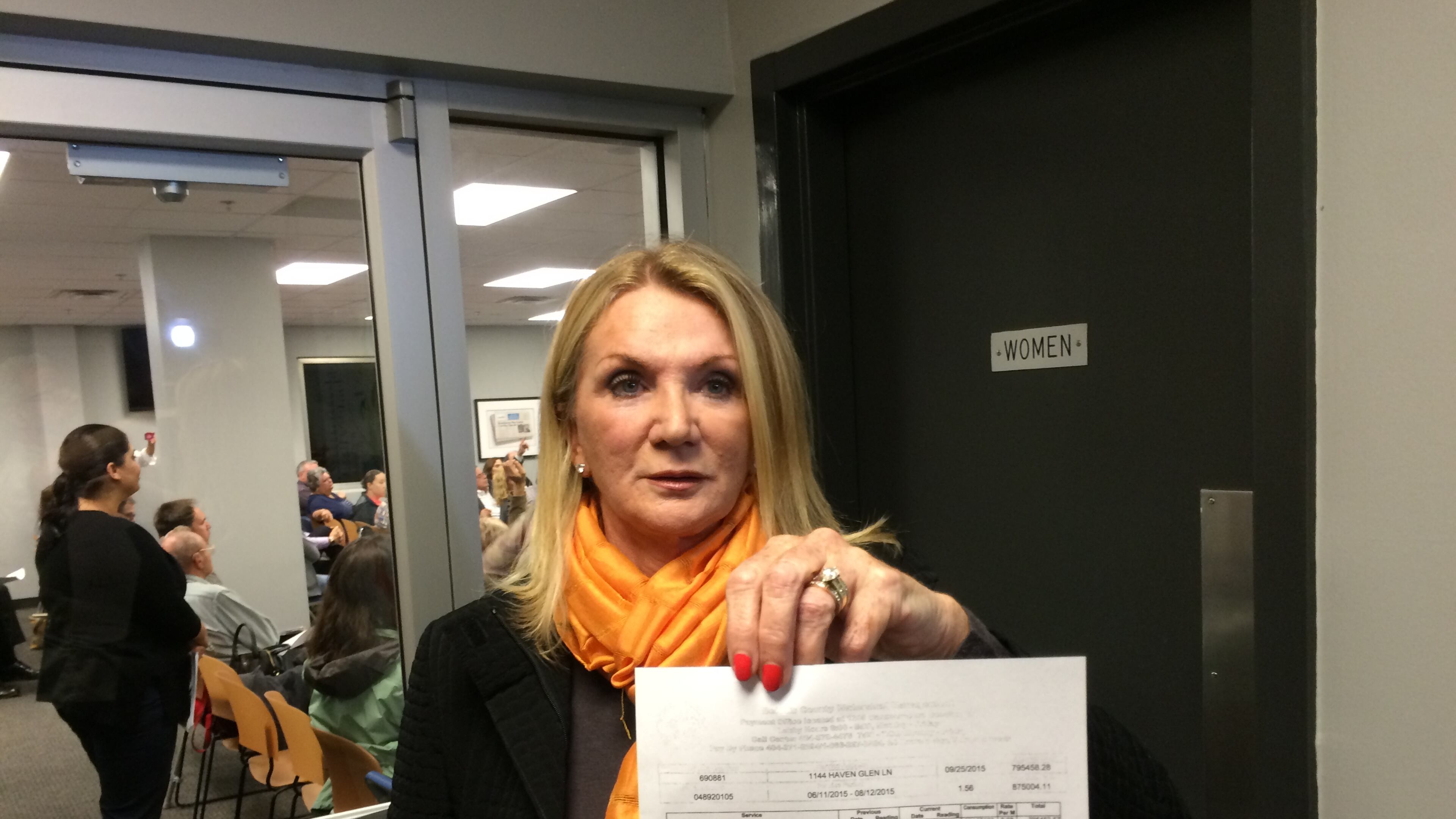 Perri Higbie shows a $795,458 water bill that her Brookhaven homeowners' association received from DeKalb County in August. Higbie and about 100 residents attended a water billing community meeting on Nov. 2, 2015. MARK NIESSE / MARK.NIESSE@AJC.COM