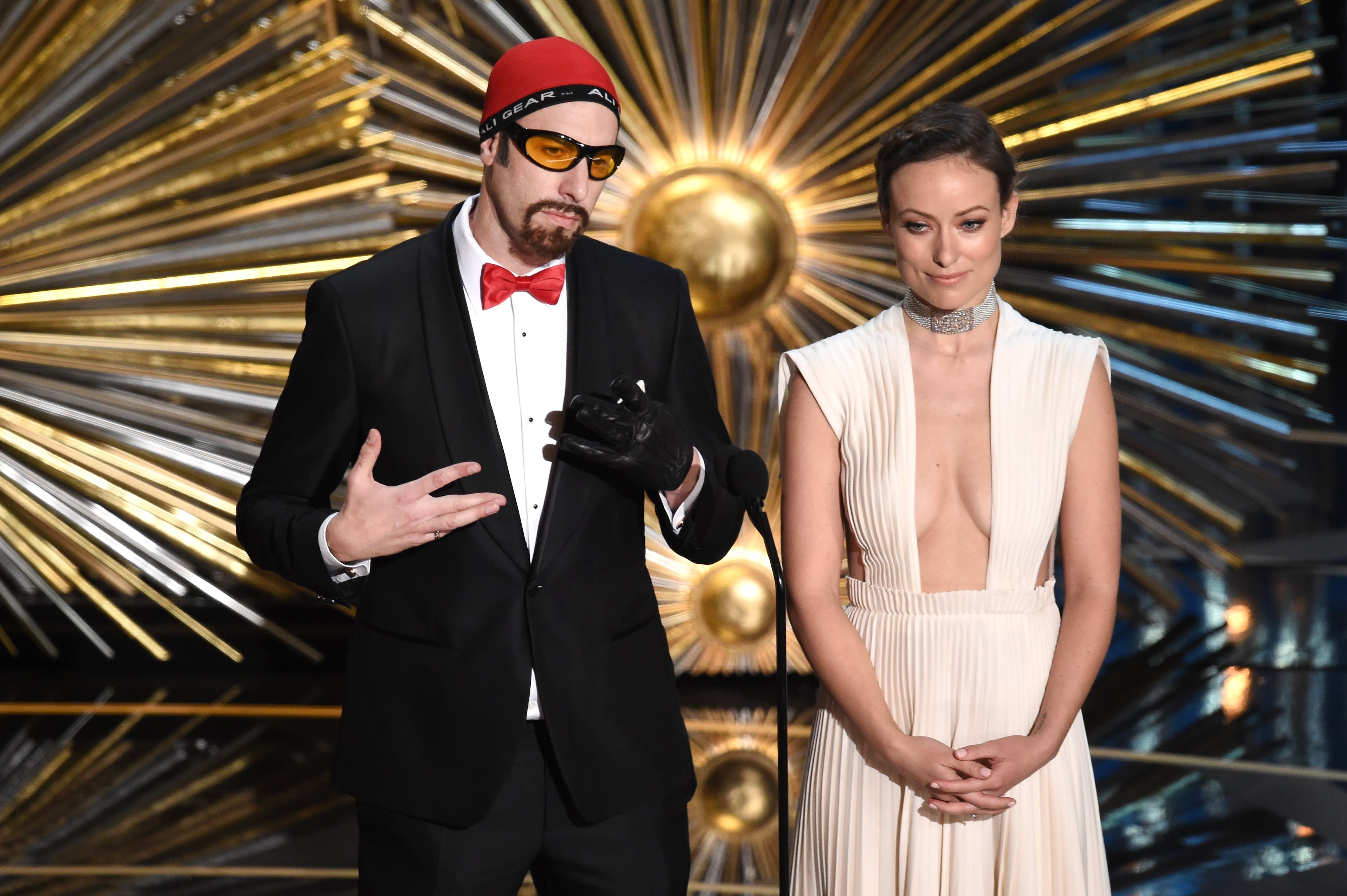 HOLLYWOOD, CA - FEBRUARY 28: Actors Sacha Baron Cohen (L) and Olivia Wilde speak onstage during the 88th Annual Academy Awards at the Dolby Theatre on February 28, 2016 in Hollywood, California. (Photo by Kevin Winter/Getty Images)