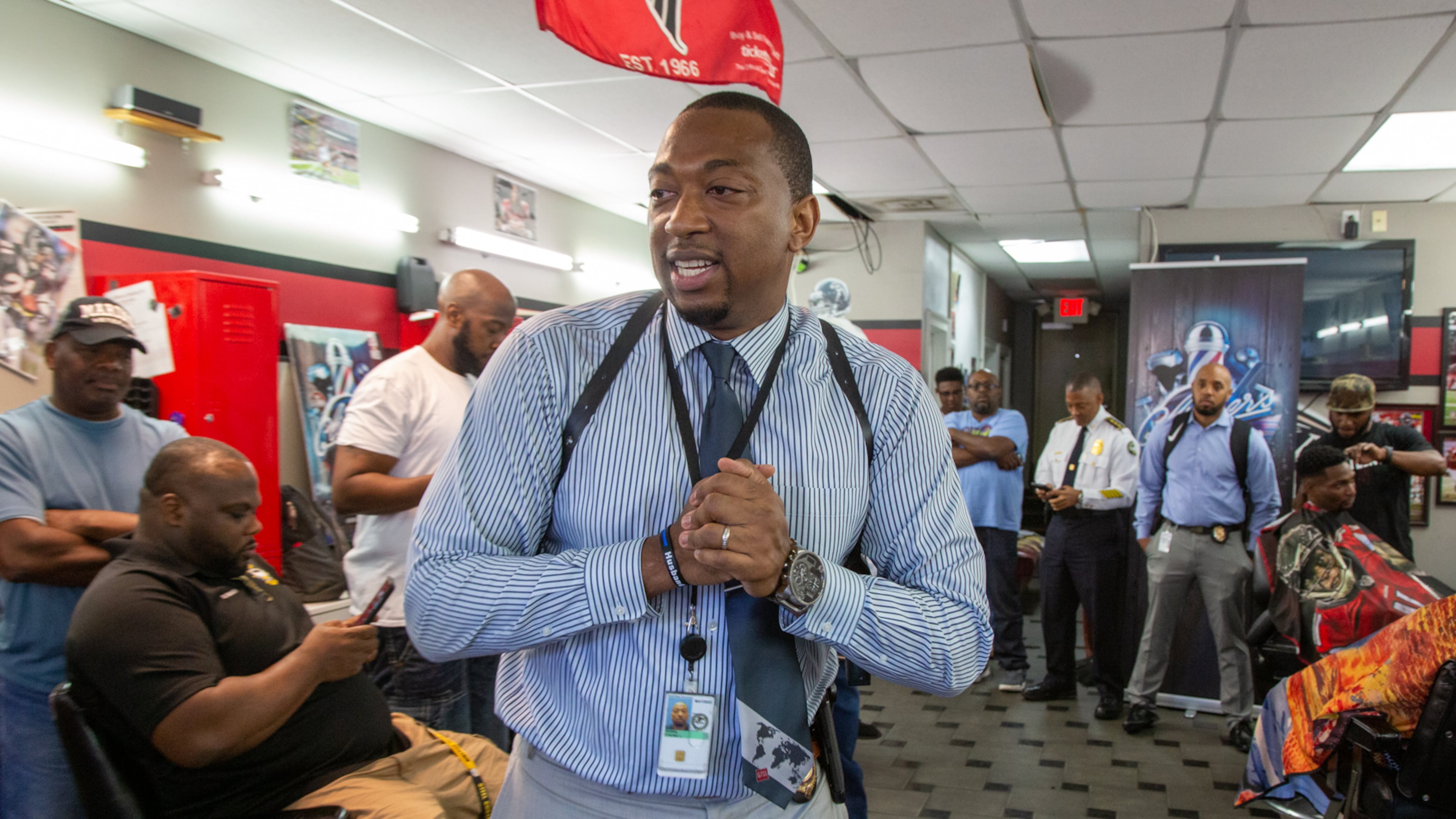 Tyrone Dennis leads a discussion with community members at Pro Cuts ATL, a barber shop off Martin Luther King in Atlanta. The Investigator with the Atlanta Police Department is trying to build better relations between cops and the community with informal gatherings called "Clippers & Cops," when there is no cause for confrontation. (Photo by Phil Skinner)