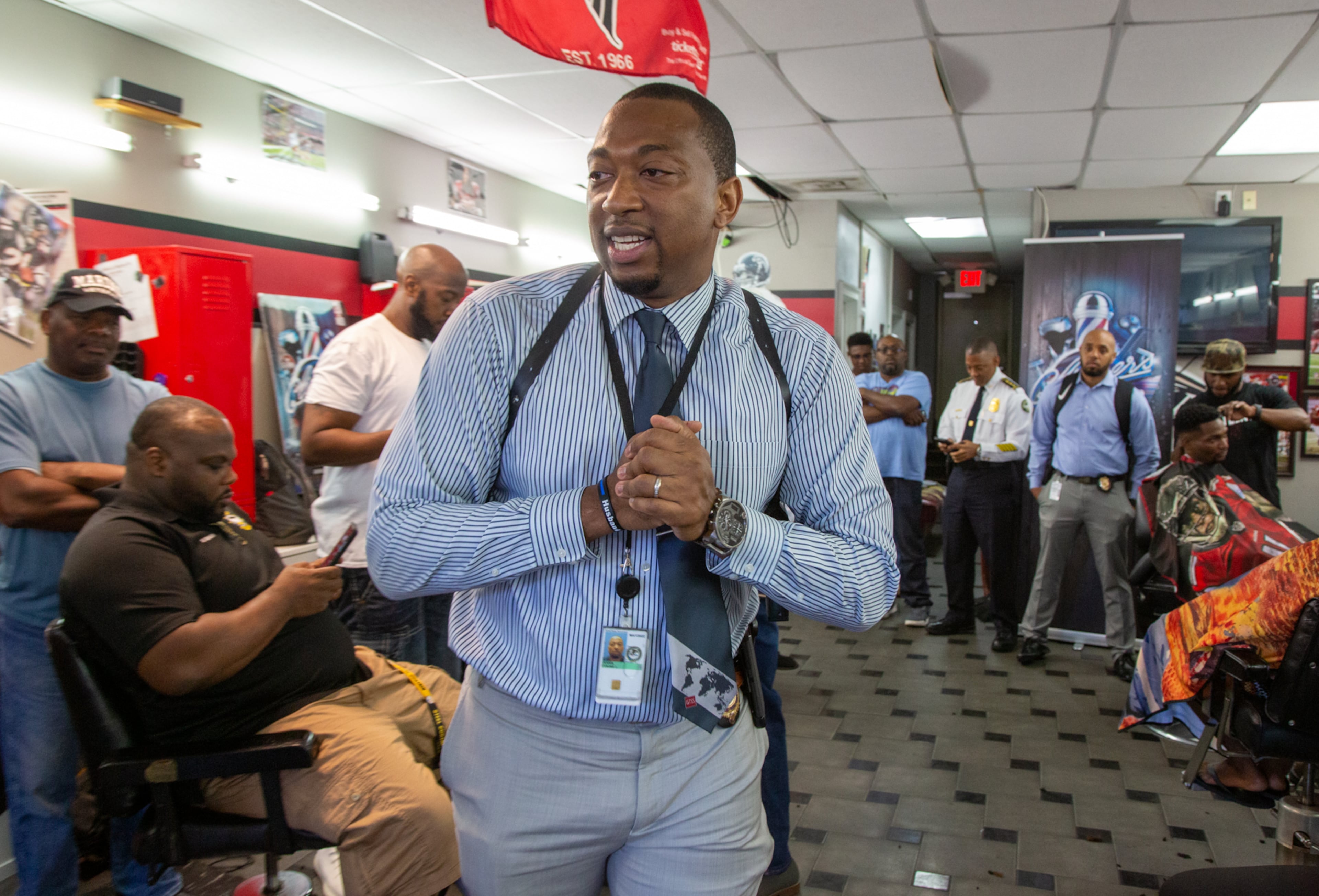 Tyrone Dennis leads a discussion with community members at Pro Cuts ATL, a barber shop off Martin Luther King in Atlanta. The Investigator with the Atlanta Police Department is trying to build better relations between cops and the community with informal gatherings called "Clippers & Cops," when there is no cause for confrontation. (Photo by Phil Skinner)