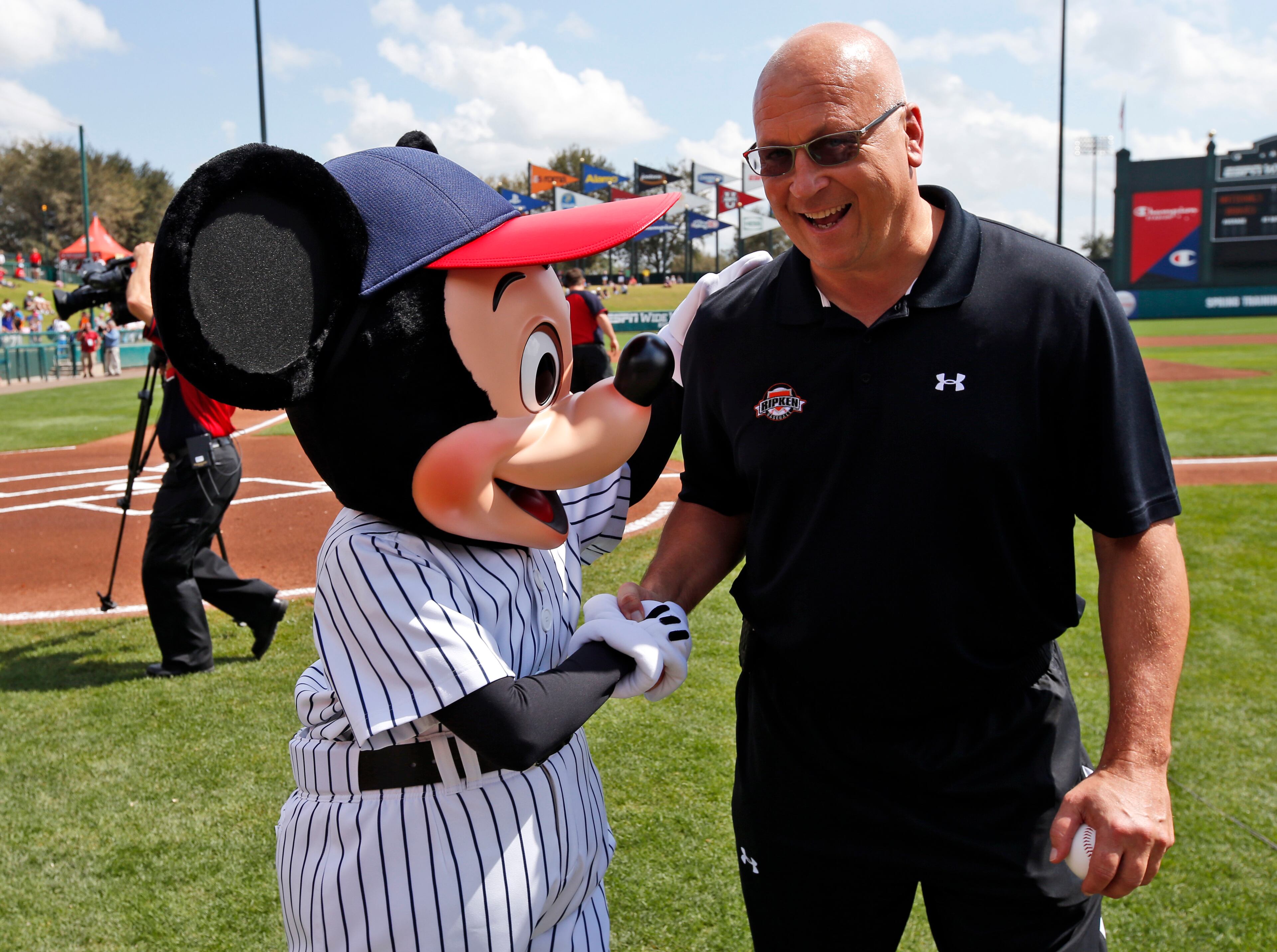 Mickey Mouse, left, greets former Baltimore Orioles player Cal Ripkin Jr., after Ripkin threw out a ceremonial first pitch before a spring exhibition baseball game between the Atlanta Braves and Washington Nationals, Tuesday, March 4, 2014, in Kissimmee, Fla.